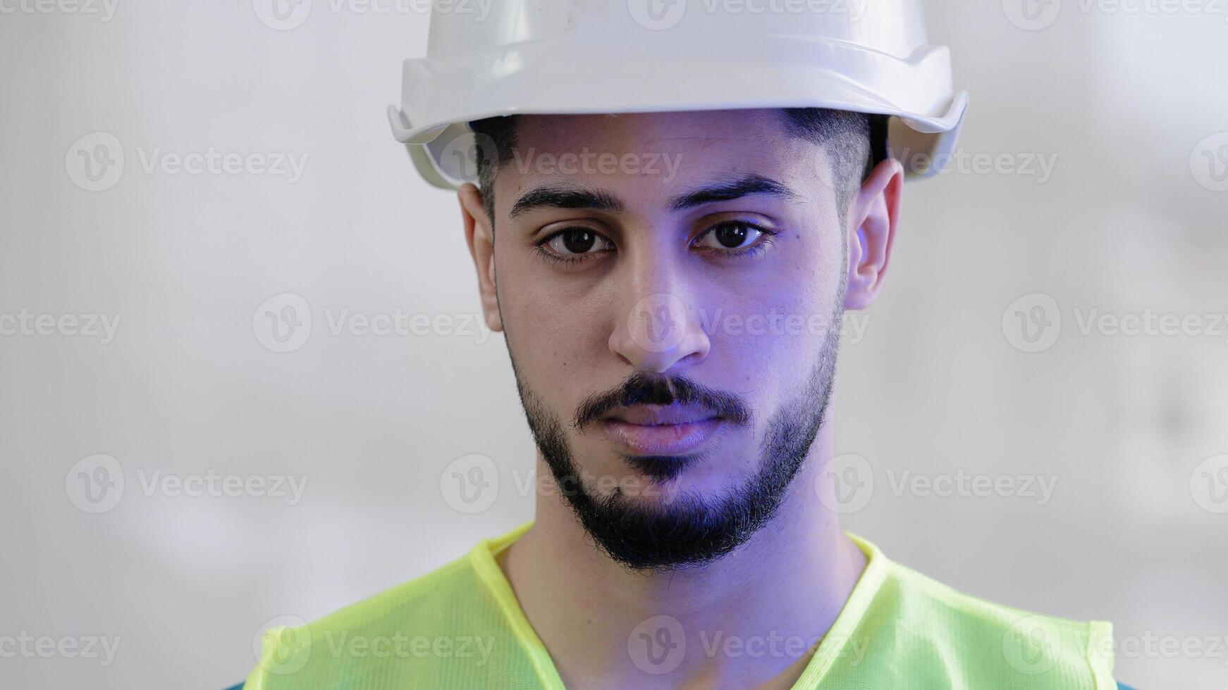 Close-up portrait serious hispanic man contractor mechanic male builder wear special uniform safety helmet looking at camera confident arabian engineer foreman posing with emergency light background photo