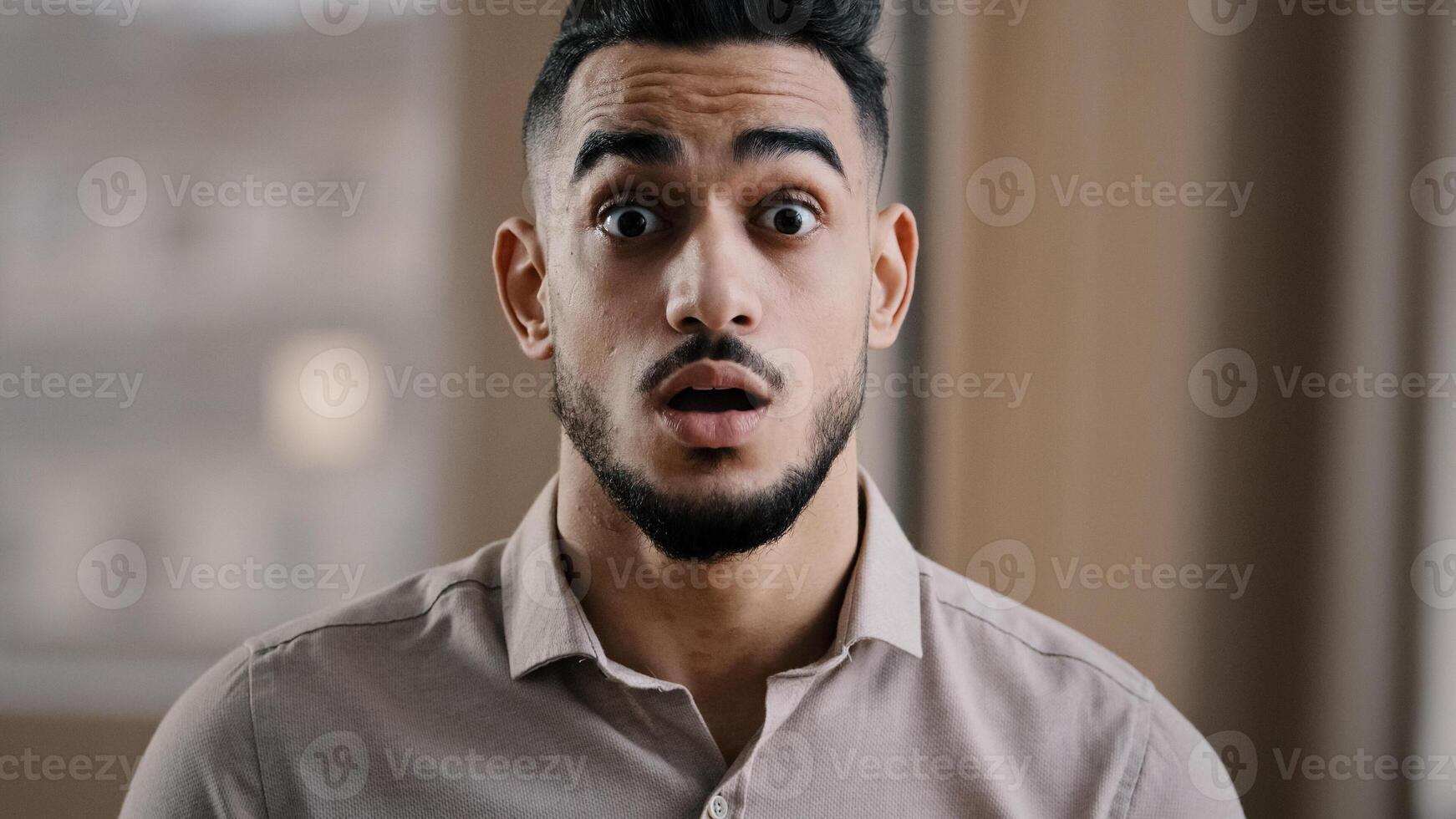 Close up shocked happy young hispanic male business man professional worker surprised looking at camera make big eyes rejoice victory amazed guy winner demonstrate wow reaction joyful face expression photo