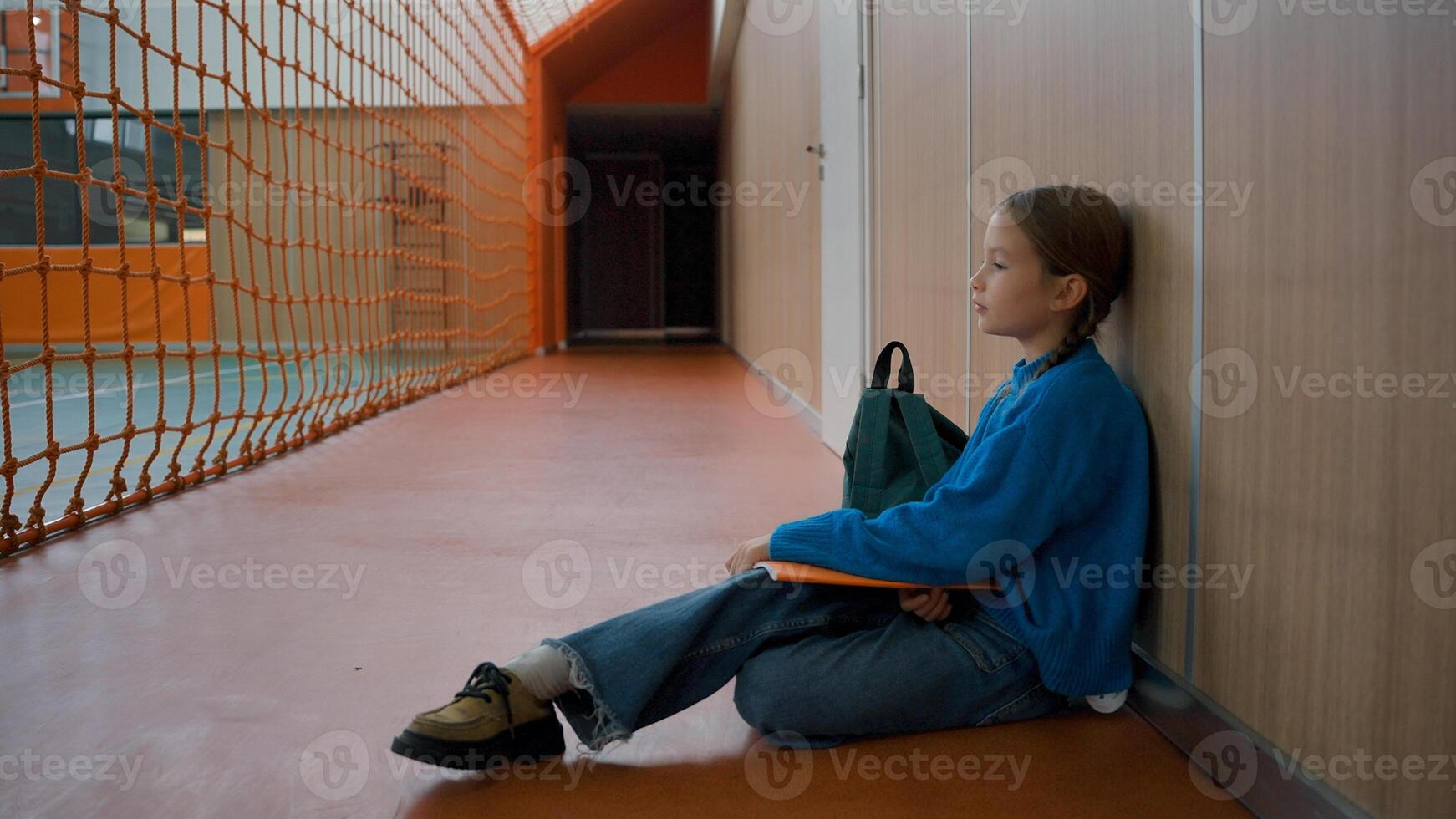 Unhappy little girl sitting floor gym tired primary school lesson schoolgirl fatigue weary child alone frustrated inside stress kid learner sport physical activity pupil education exam break exercise photo