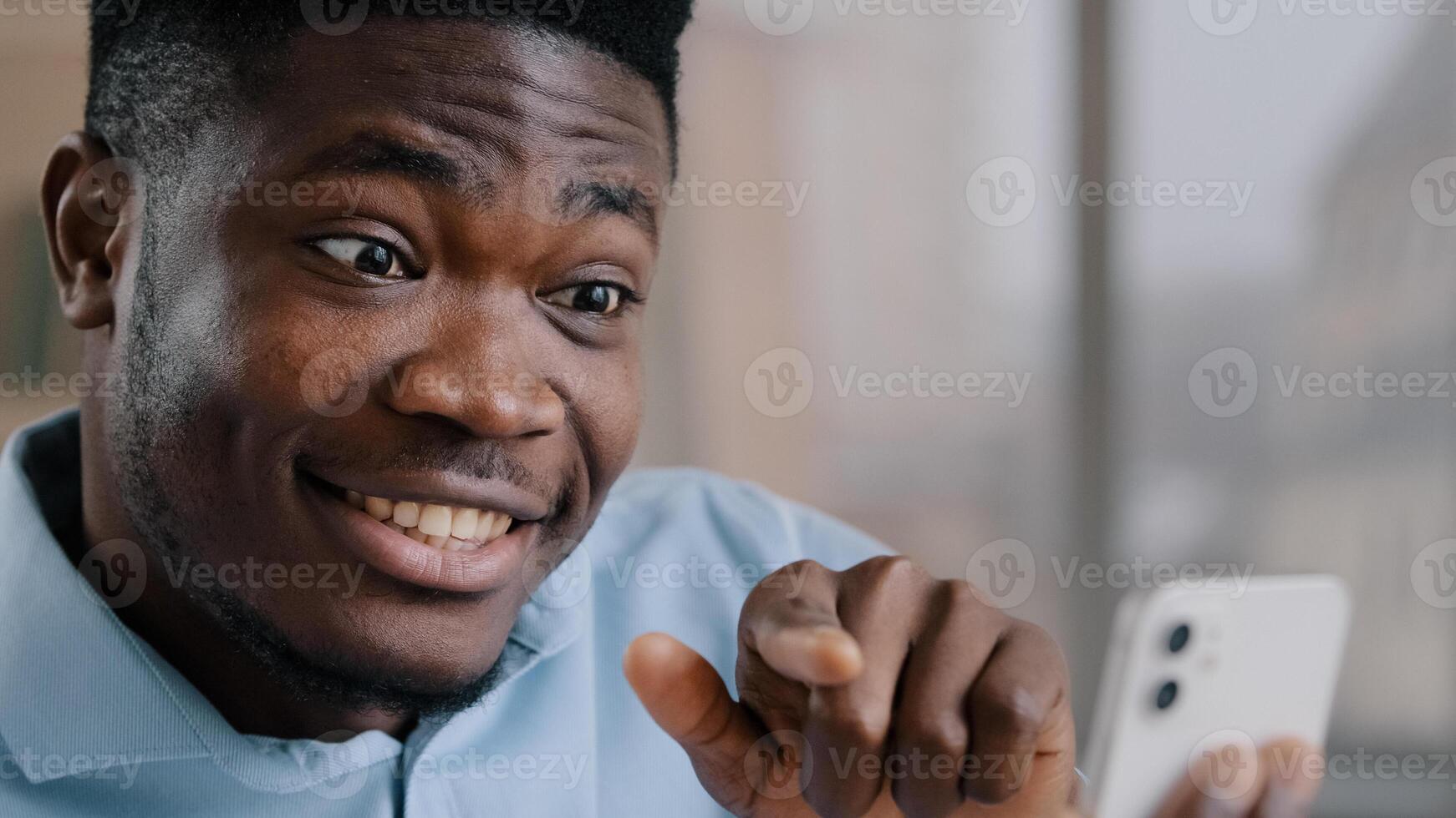 Smiling happy african man businessman adviser american brunet guy expert hold mobile phone look at display smartphone gadget greet friend by call communicate in virtual chat remote consultation photo
