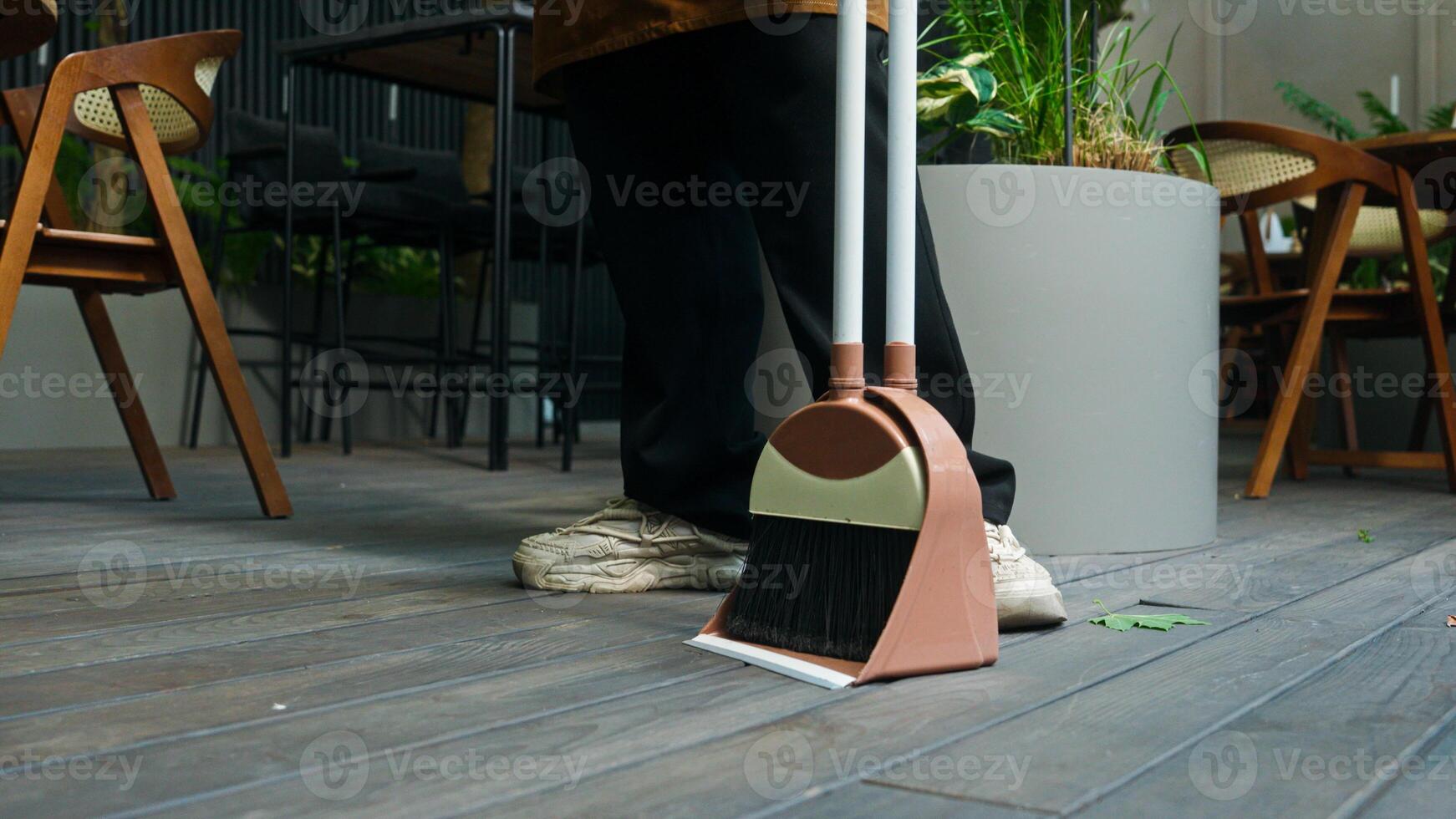 Tired exhausted Indian Arabian ethnic male man guy in apron waiter cleaner barista street food worker sweeping dirt broom cleaning finish working wiping sweat forehead at city cafeteria small business photo