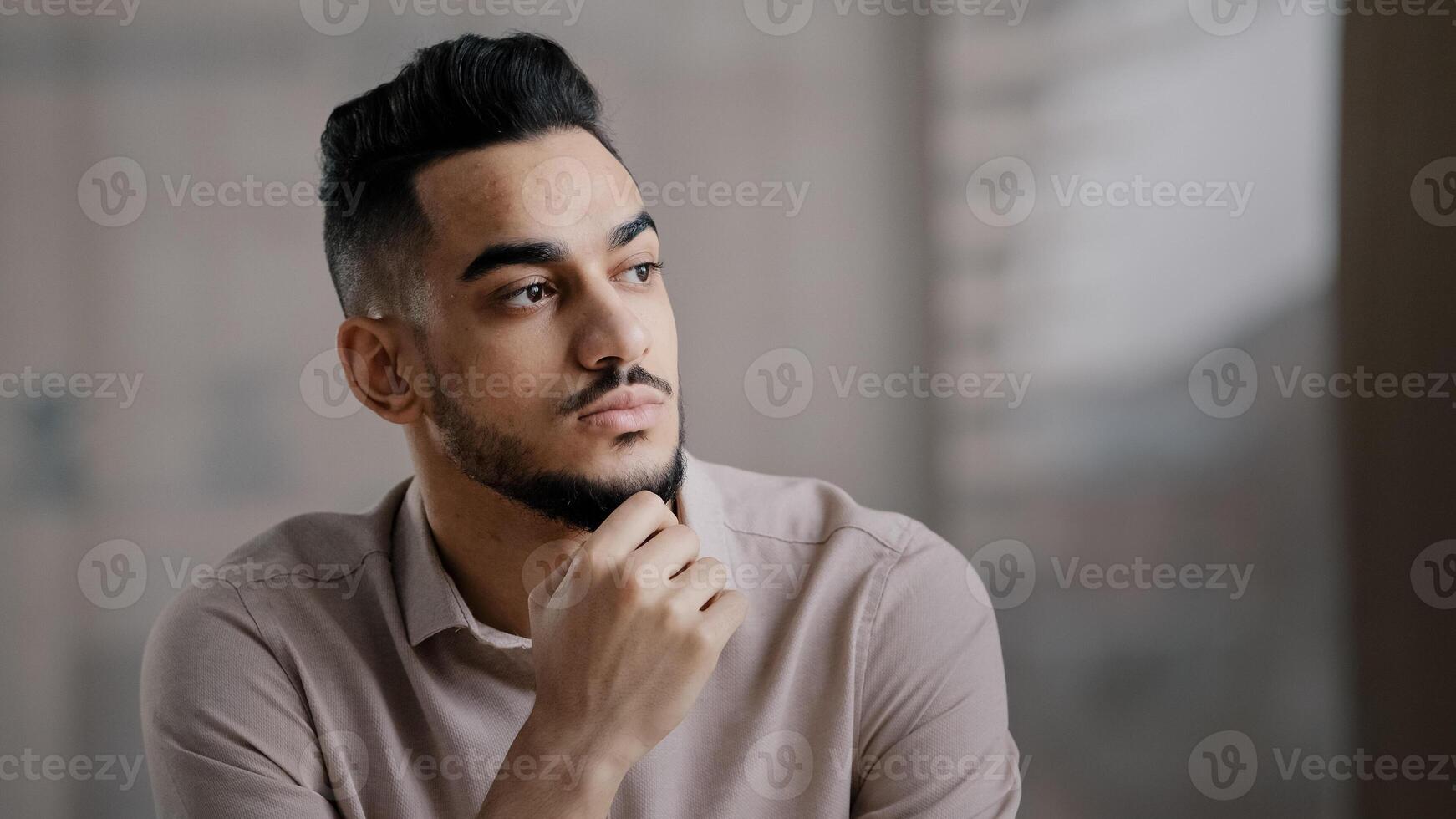 Thoughtful serious young hispanic man guy doubtful male professional worker sit at home office desk look away hold hand on chin lost in thoughts search for inspiration new idea make difficult decision photo