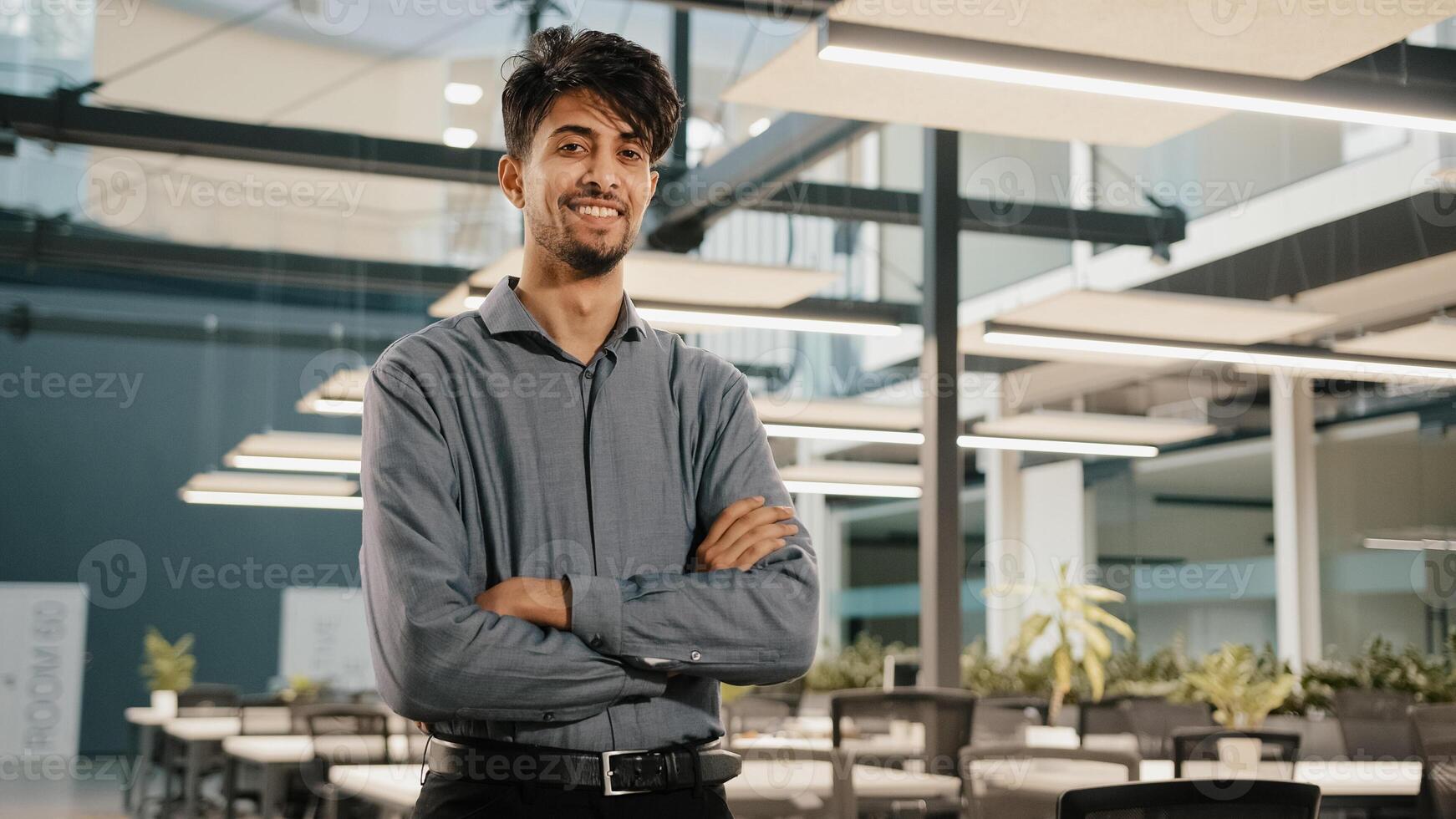 Confident smiling indian business man male financial analyst employee professional worker stand in office with crossed arms arabian handsome adult investor posing look at camera happy face expression photo