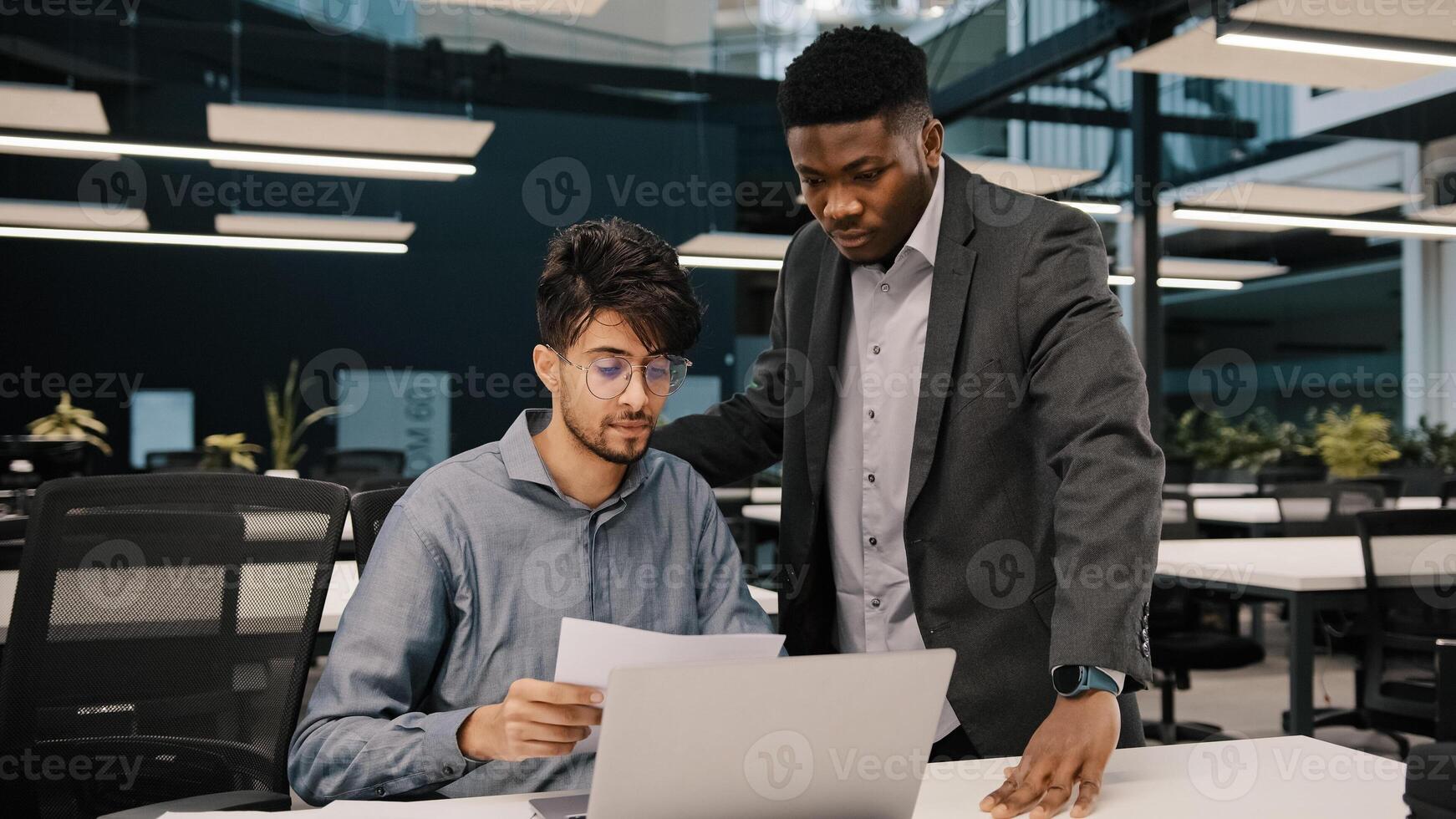 Male african mentor financial advisor businessman boss helping arab man colleague discussing marketing result in report paperwork american supervisor training partner giving business advice at office photo