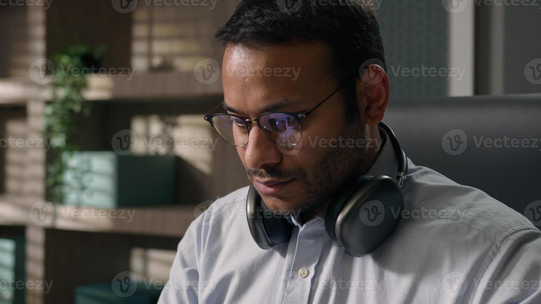 Satisfied happy American businessman Indian man Arabian worker business entrepreneur finish work complete task job done close laptop put legs on office table relax listen music in headphones relaxing photo