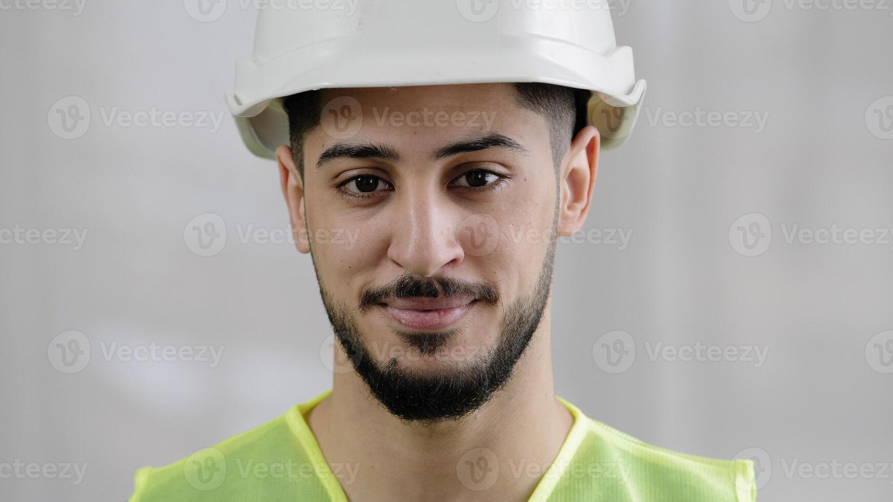 Front view male professional inspector arab man builder mechanic engineer worker wear special uniform hard hat smiling hispanic foreman posing for camera flash pleased with inspecting manufacture work photo