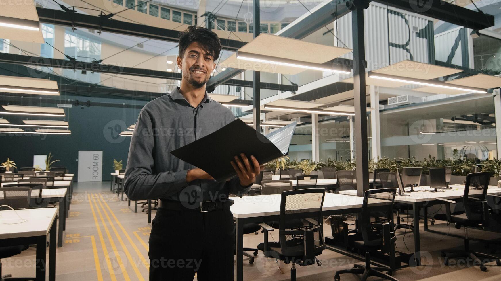 Young indian latin manager male business man employee checking document folder inspecting financial report raising head with satisfied look winking eye approvingly giving consent working agreement photo