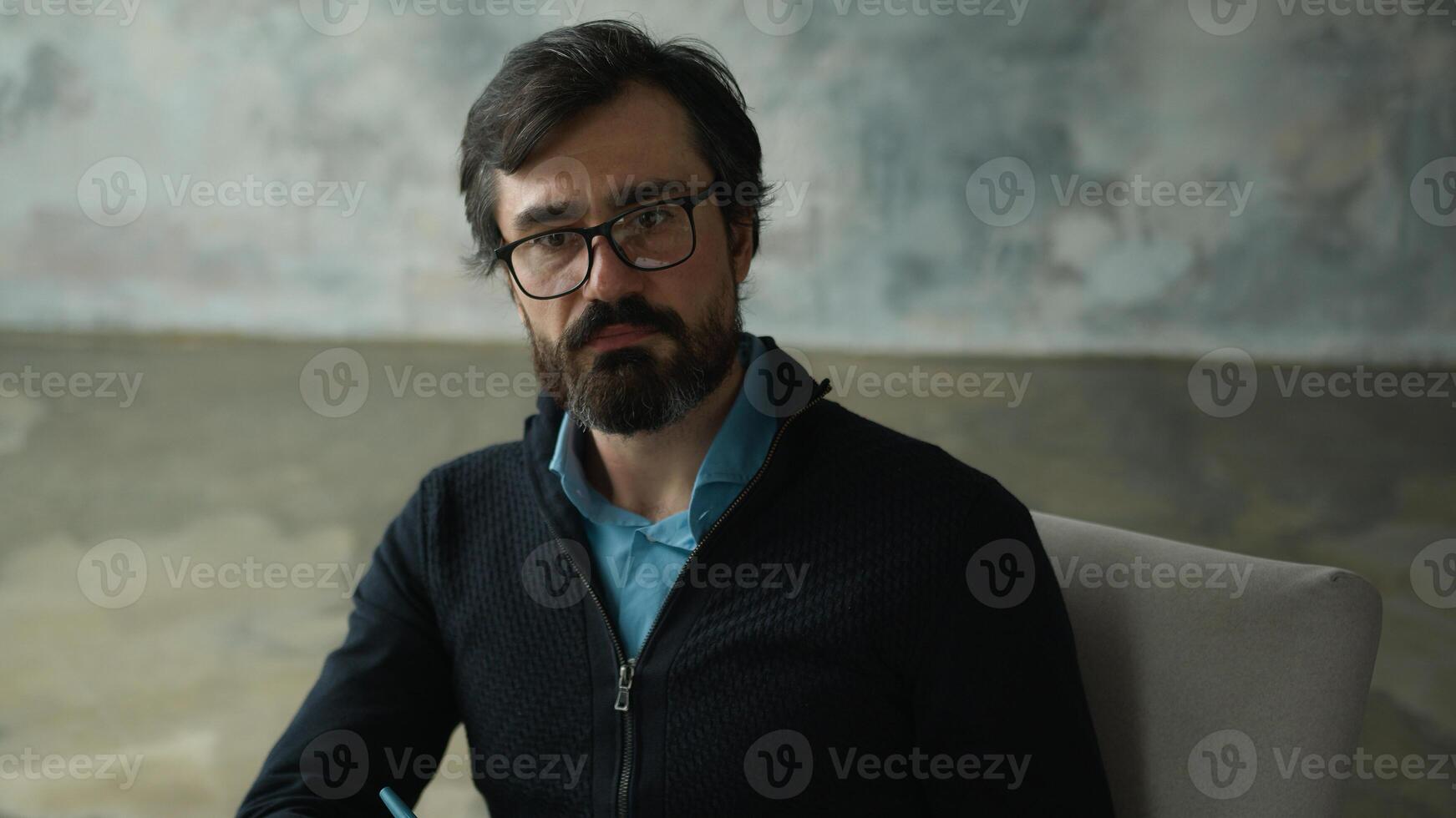 Attentive serious Caucasian middle aged man psychologist male psychotherapist in eyeglasses listening patient listen client writing notes write information clipboard counseling service session cabinet photo