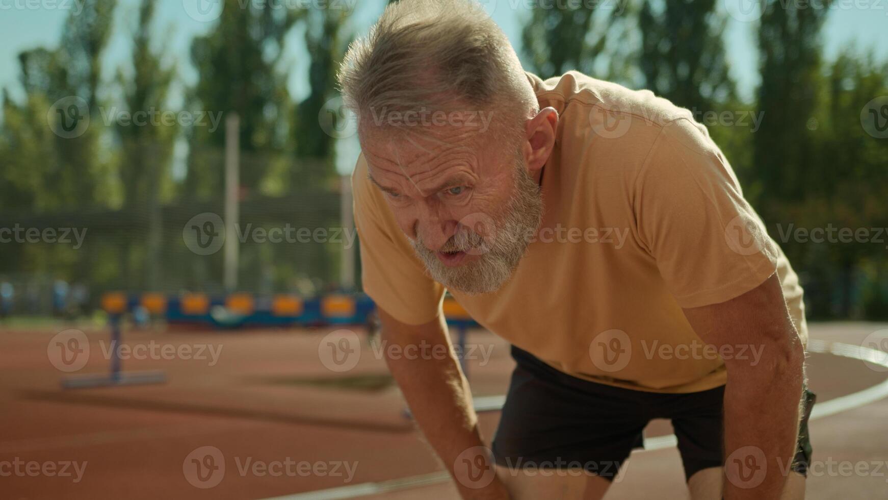 Caucasian exhausted elderly man runner tired jogging sport activity healthy lifestyle stadium outside running exercise fitness training outdoors old senior male have break rest hard breathing dyspnea photo