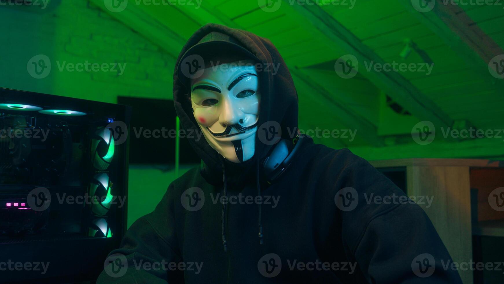 Lviv, Ukraine - June 03, 2024. Man in mask using mobile phone smartphone anonymous looking at camera technology program secure stealing danger banking cyber crime virtual hack binary password computer photo