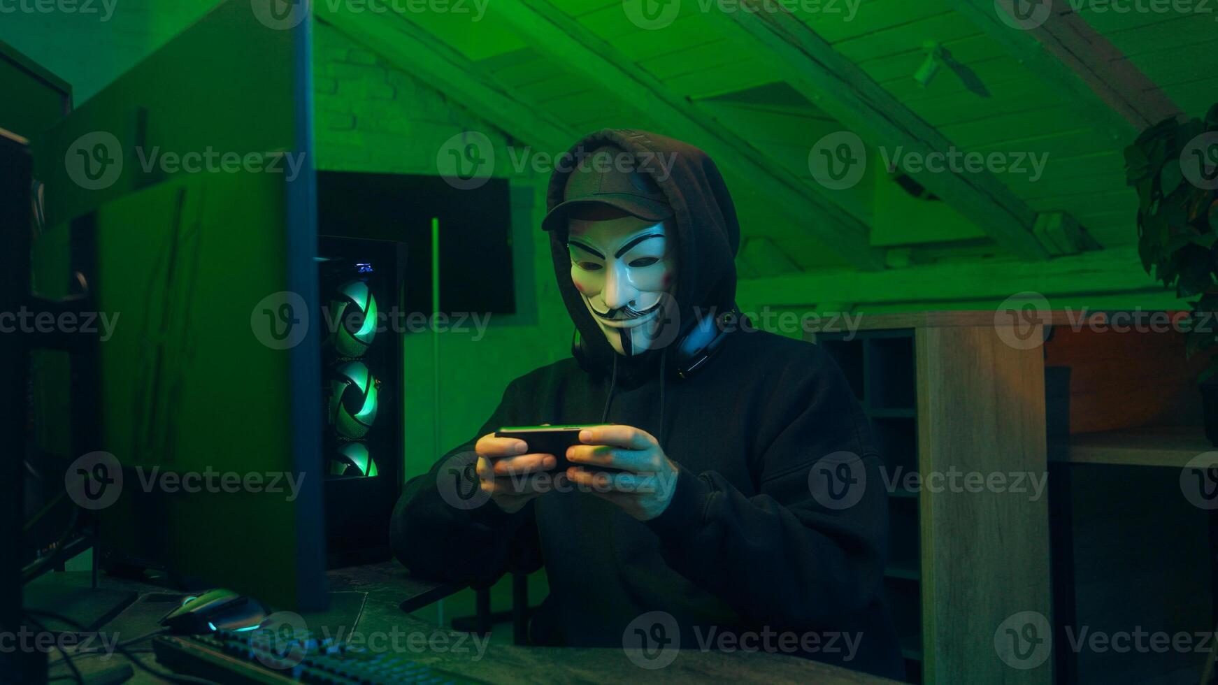 Lviv, Ukraine - June 03, 2024. Man in mask using mobile phone smartphone anonymous looking at camera technology program secure stealing danger banking cyber crime virtual hack binary password computer photo