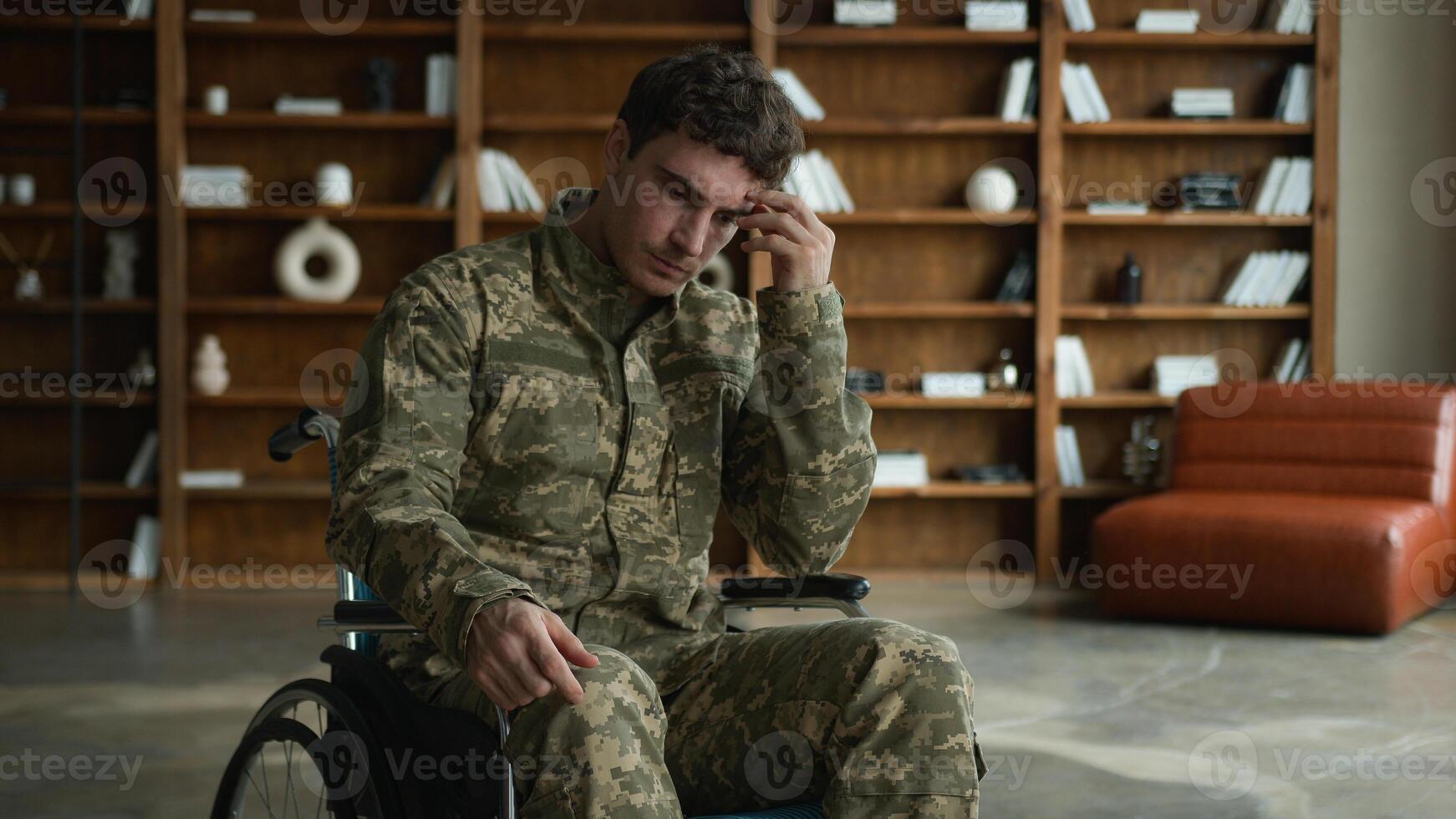 Sad anxious Caucasian male officer combat uniform man with disability military army soldier guy veteran in wheelchair touching chin face thinking ponders deep thoughts at psychotherapy session office photo