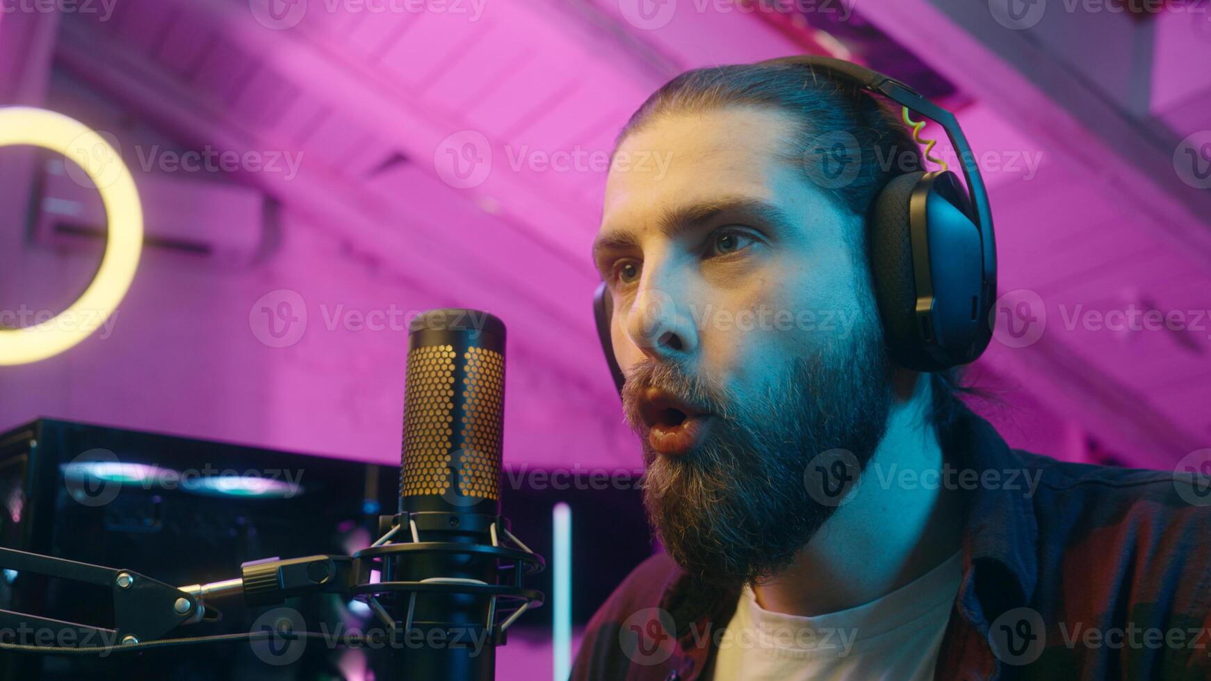 Focused glad Caucasian man gamer stream commenting game in microphone look monitor male play virtual strategy online cyber sport addict tense player blogger screaming win successful match victory home photo