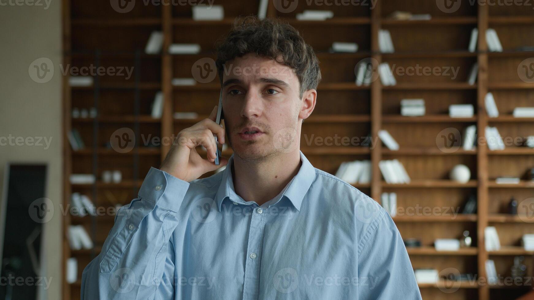 Professional young Caucasian male business man guy businessman employer entrepreneur worker negotiate talk smartphone calling mobile phone cellphone speaking consulting client indoors office cabinet photo