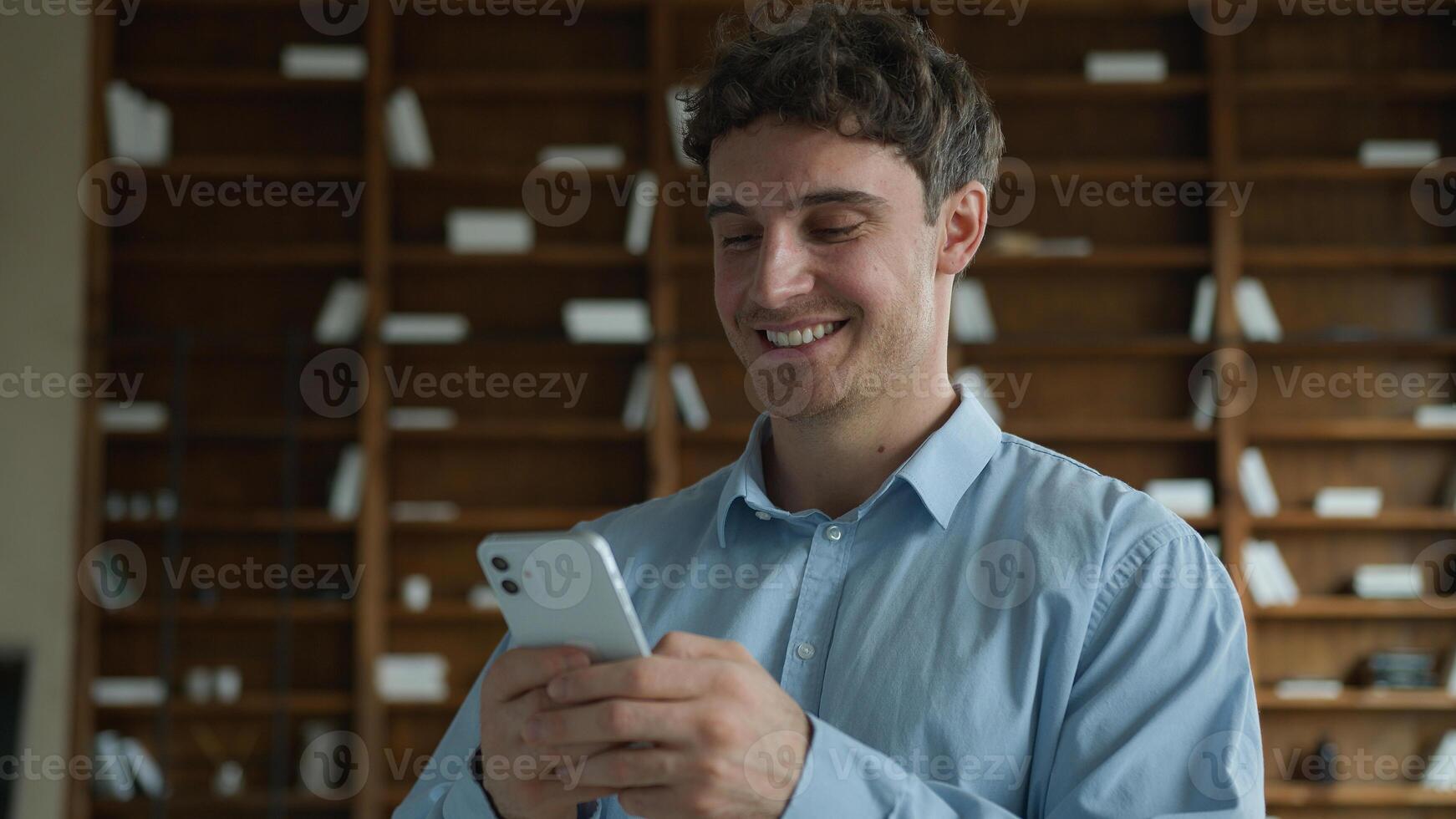 Smiling gen z happy Caucasian business man European male wide smile guy businessman relaxed boss use mobile phone texting online chat sending internet messages scrolling device inside apartment office photo