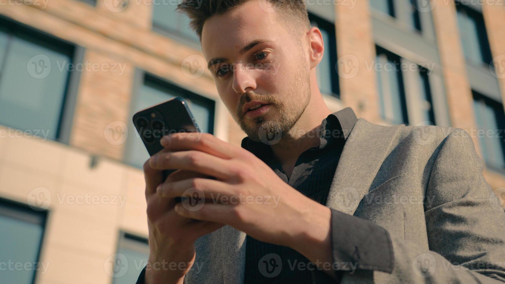 Surprised amazed Caucasian man receiving email message on phone in city outdoors shocked male guy businessman reading news on social network in Internet using smartphone on street checking SMS chat photo