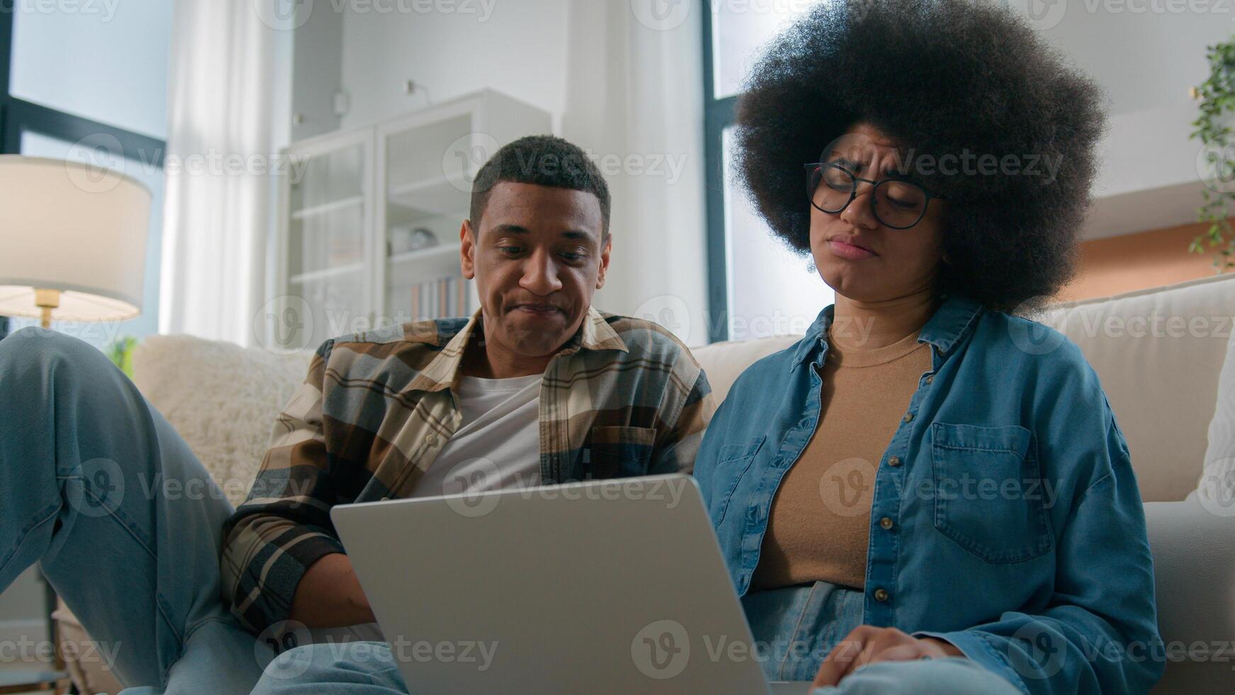 African American couple on floor at home using online laptop computer browsing shopping together pay bills choose products order delivery do high five gesture teamwork happy family in own apartment photo