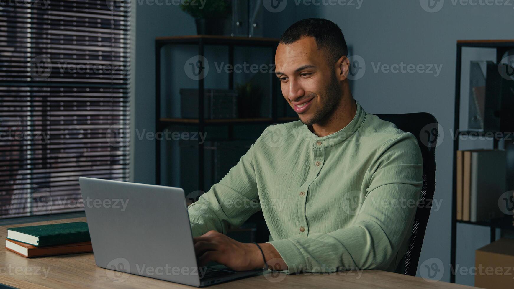 Smiling african american business man businessman guy male entrepreneur freelancer typing on laptop computer working remote on internet in home office sending email to client customer studying online photo