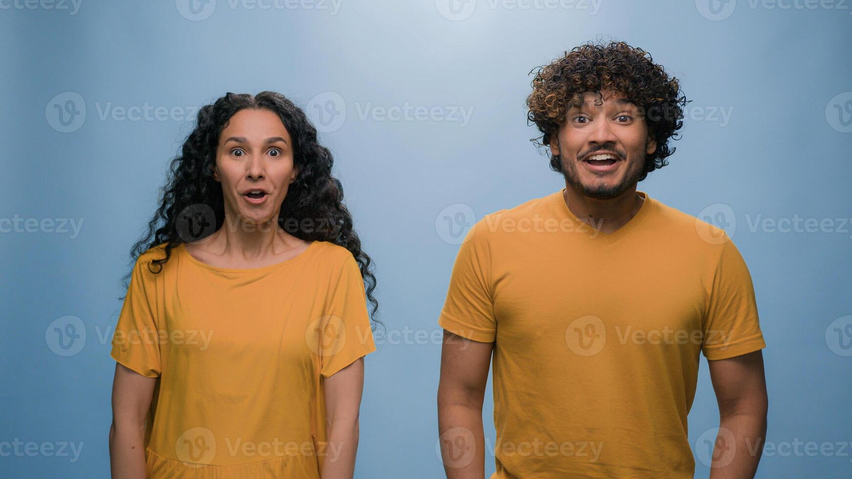Excited happy shocked wonder amazed surprised Arabian couple winners Indian man woman amazing good news achieve win victory achievement triumph shout screaming yelling winning blue studio background photo