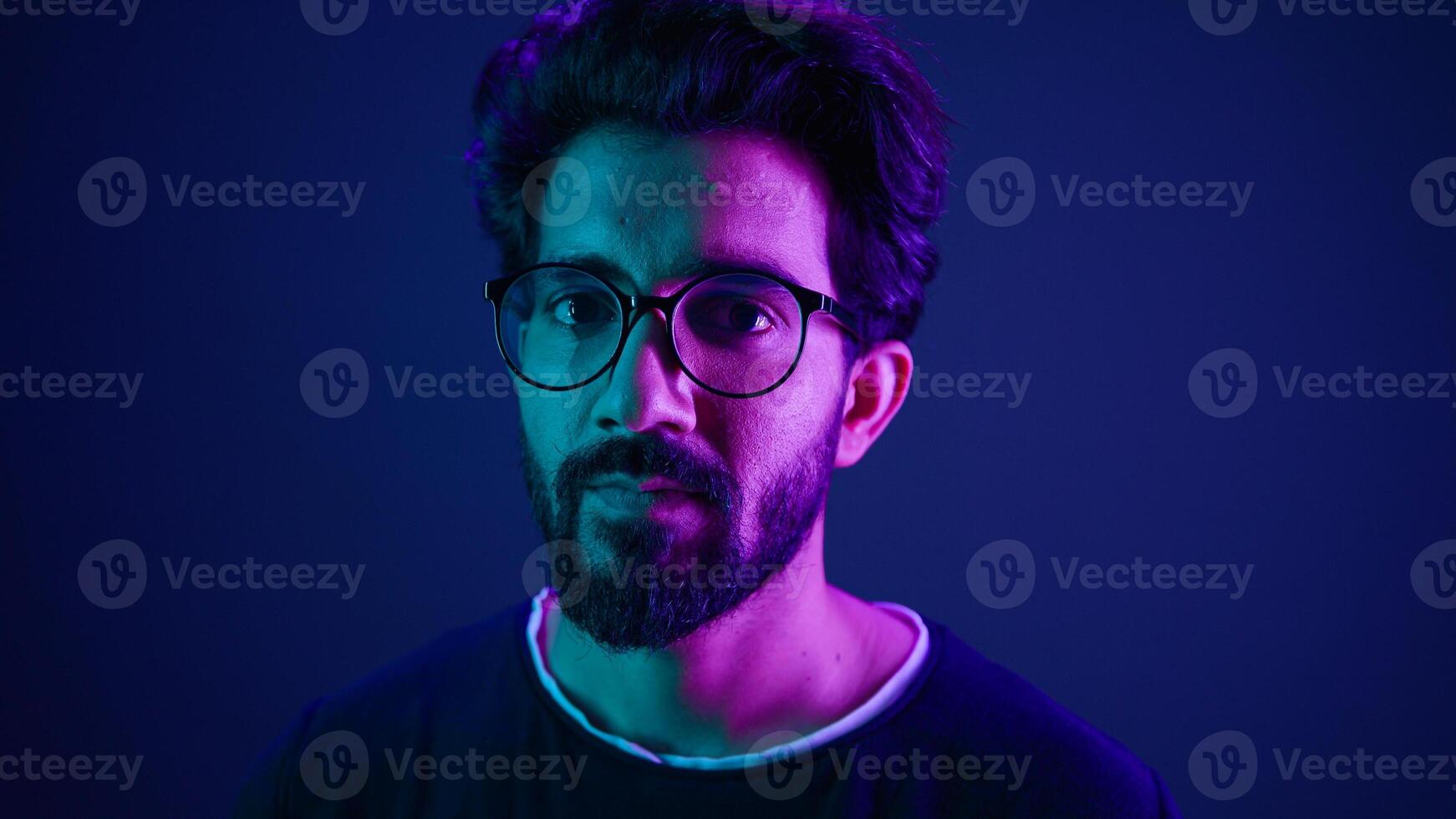 Close up portrait neon ultraviolet background Indian man guy developer coder smart hacker clever coding computer engineer showing gesture think about it thinking hard brain mental ponder IQ remember photo