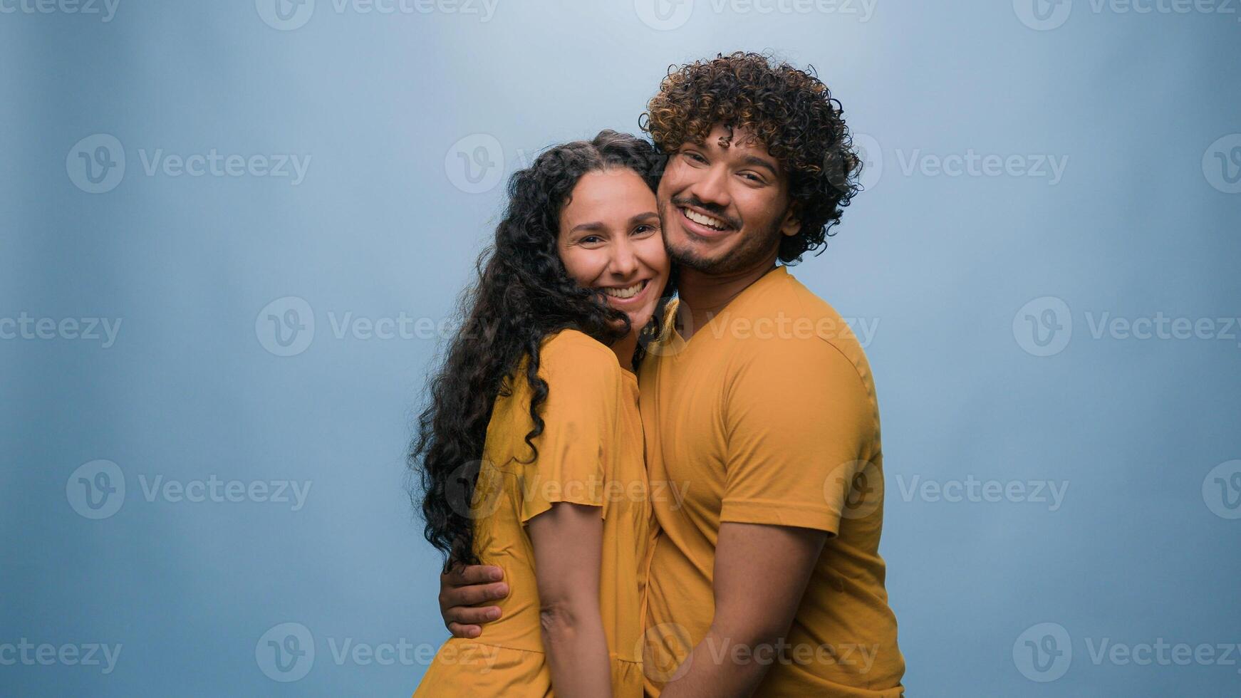 Blue studio background happy multiracial couple showing heart shape St Valentines Day romantic relationships love married man and woman sincere feelings followers kindness volunteering Ukraine support photo