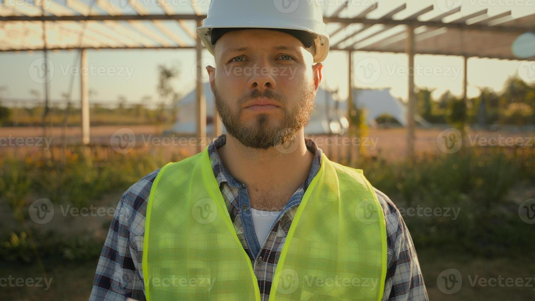 Close up portrait thoughtful serious Caucasian male engineer builder man guy controller helmet uniform hold checking tablet notebook looking camera outdoors countryside. Ecology industrial engineering photo