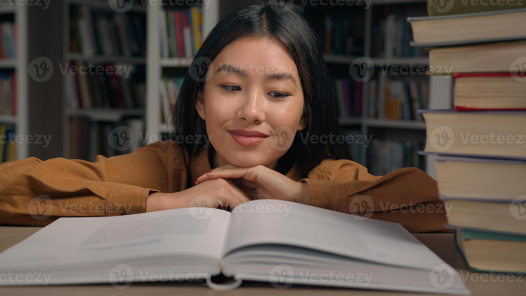Close-up asian woman student read book in university library smiling girl lady reader enjoy reading novel literature looking at textbook studying information preparing for college exam doing homework photo