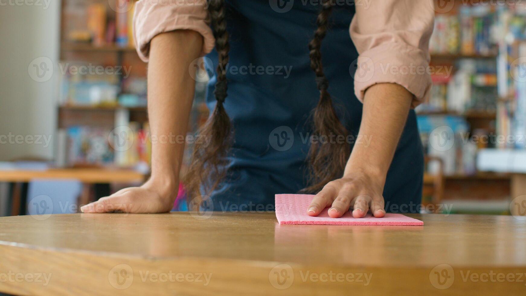 Close-up unrecognizable woman barista waitress in apron wipe table in cafe girl lady catering worker wiping cleaning restaurant clean prepare cafeteria for visitors treat surface from bacteria hygiene photo