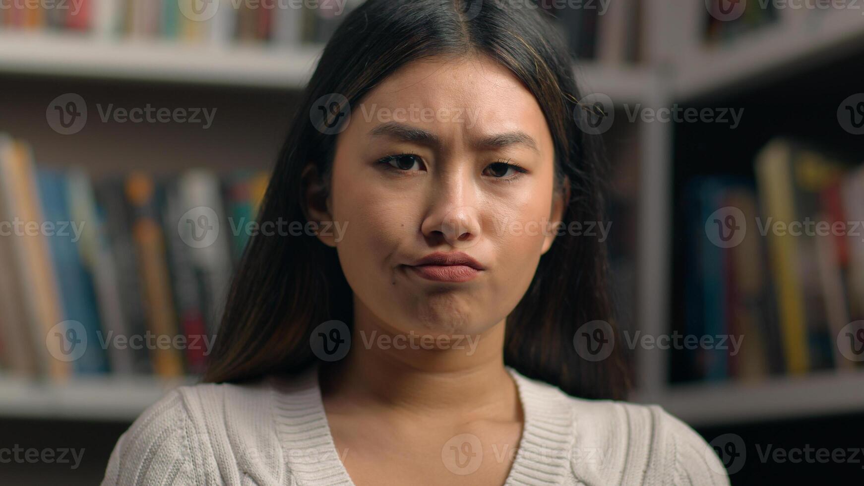 Female portrait upset sad asian woman student looking at camera with distressed frustrated expression in university library desperate girl lady feel sadness for failed result exam received bad news photo
