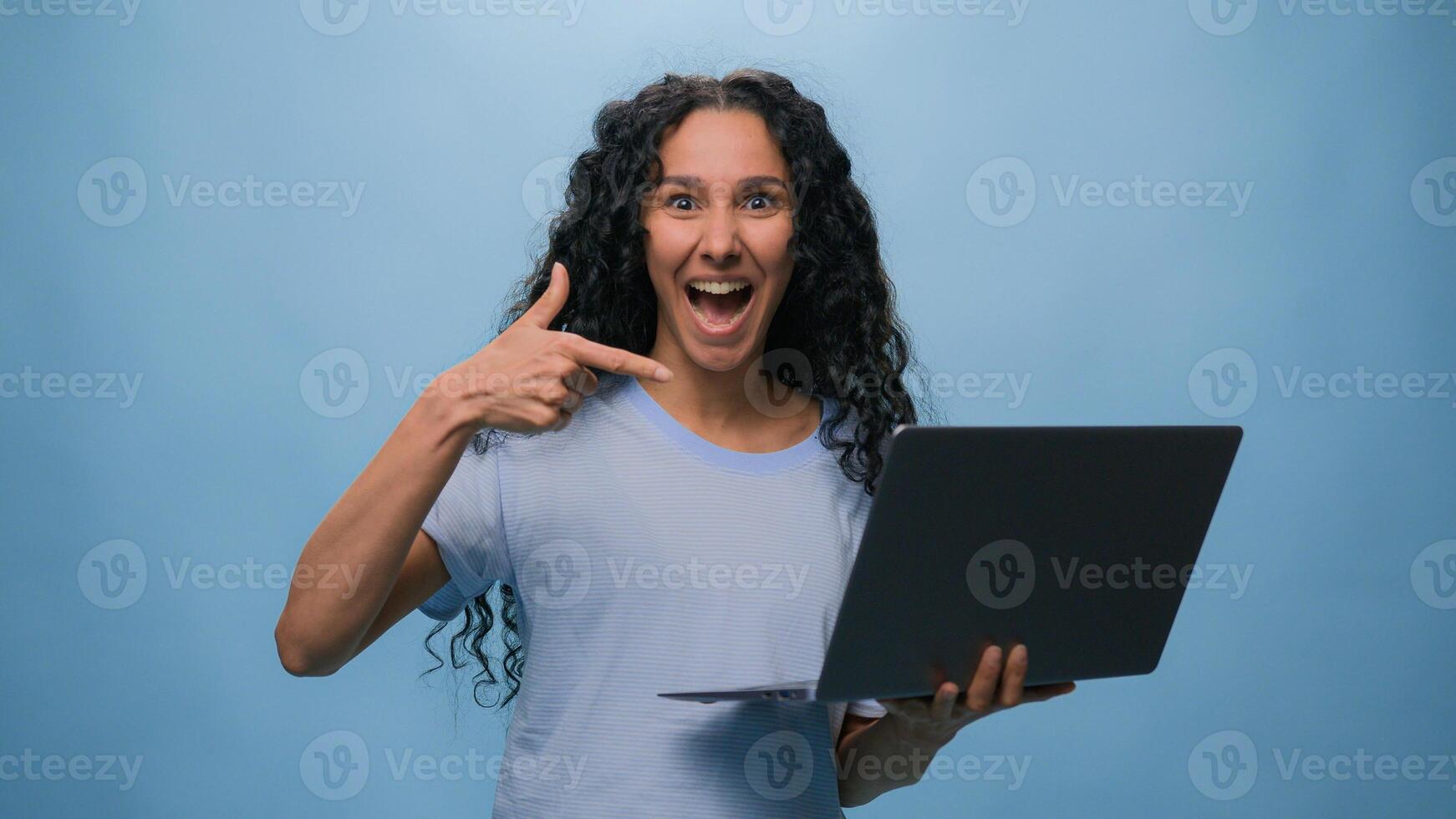 Excited woman female Latino student girl Hispanic user business win laptop online achieve victory computer bet good result champ efficient coding achievement level up bonus at blue studio background photo