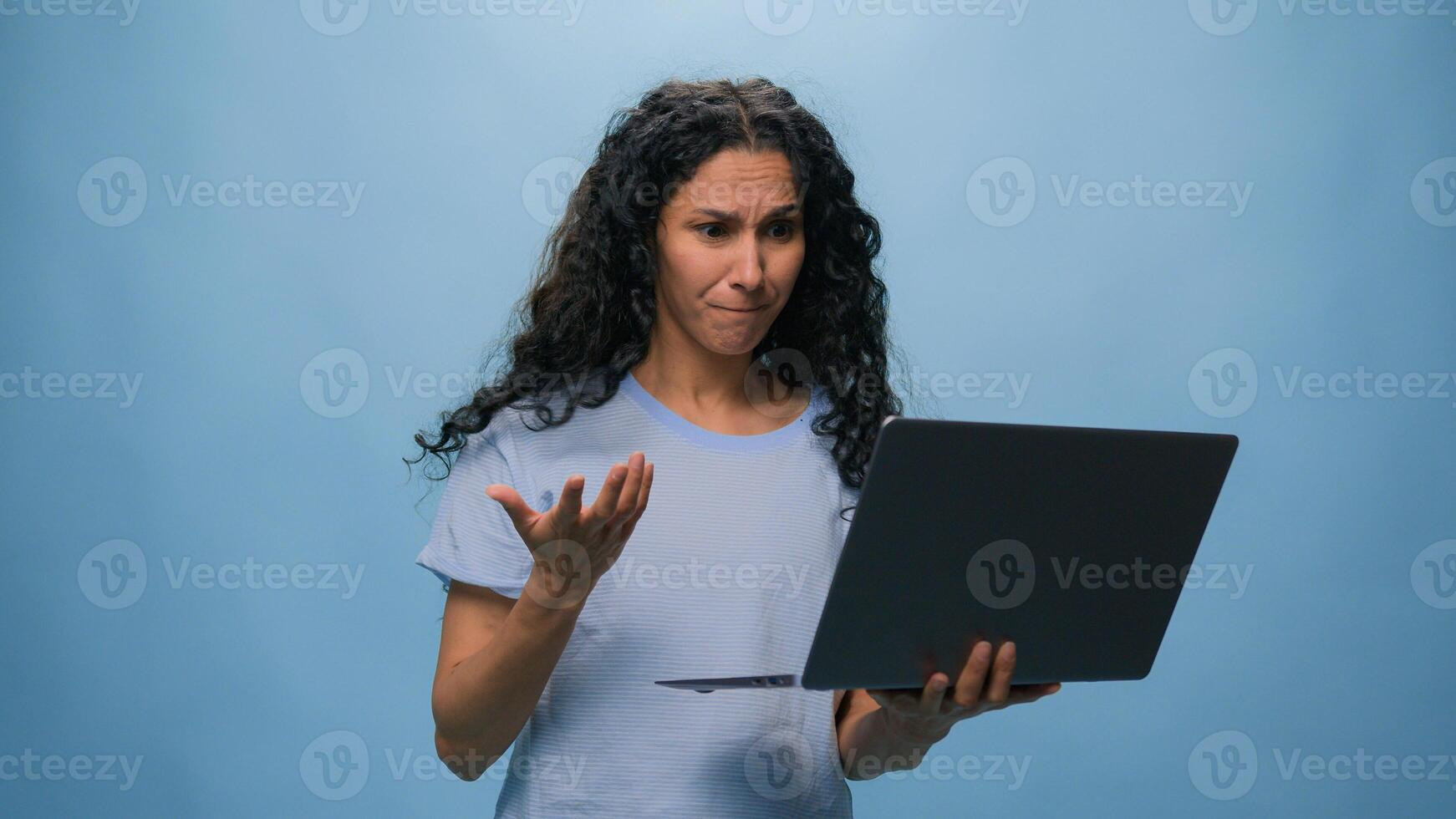 Shocked frustrated Indian student girl Latino upset woman businesswoman with computer failure stressed shock with laptop bad news business online problem failed exam results at studio blue background photo