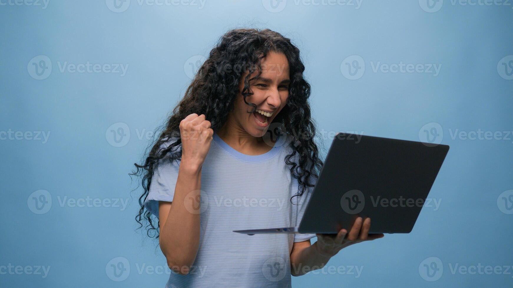 Excited woman female Latino student girl Hispanic user business win laptop online achieve victory computer bet good result champ efficient coding achievement level up bonus at blue studio background photo