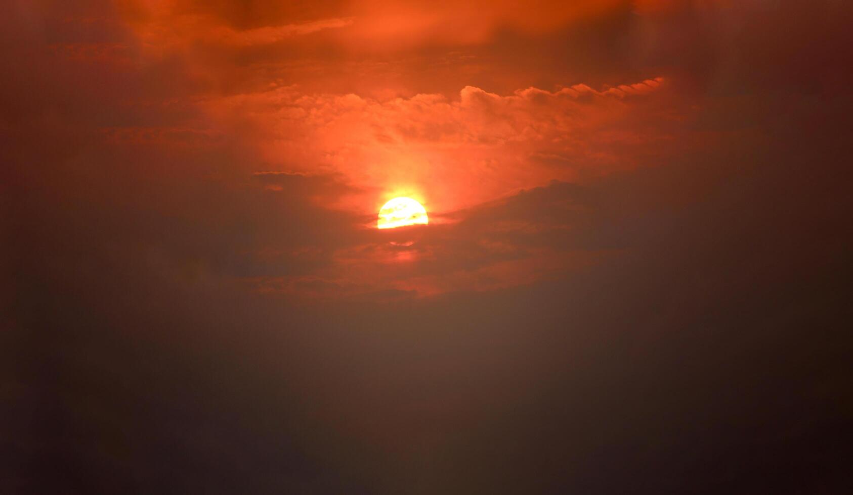 A plane flying through the sky with a bright orange sun behind it photo