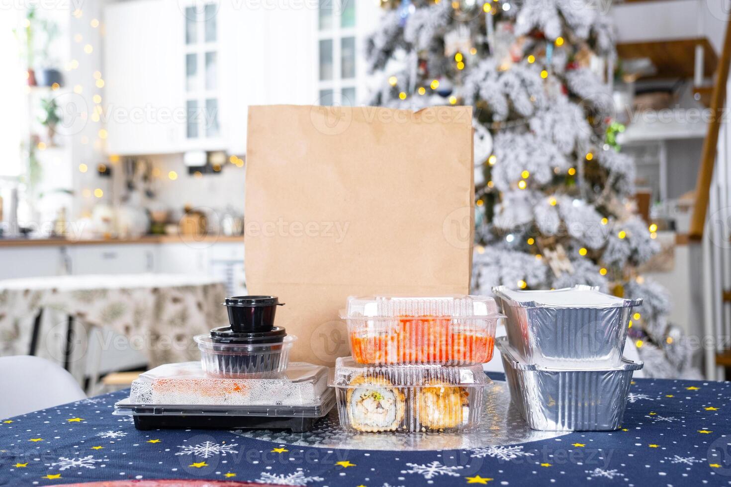 Delivery of sushi and rolls in food containers on the table in the festive interior of the kitchen of the house with a white Christmas tree for Christmas and New year. Food delivery for the holidays photo