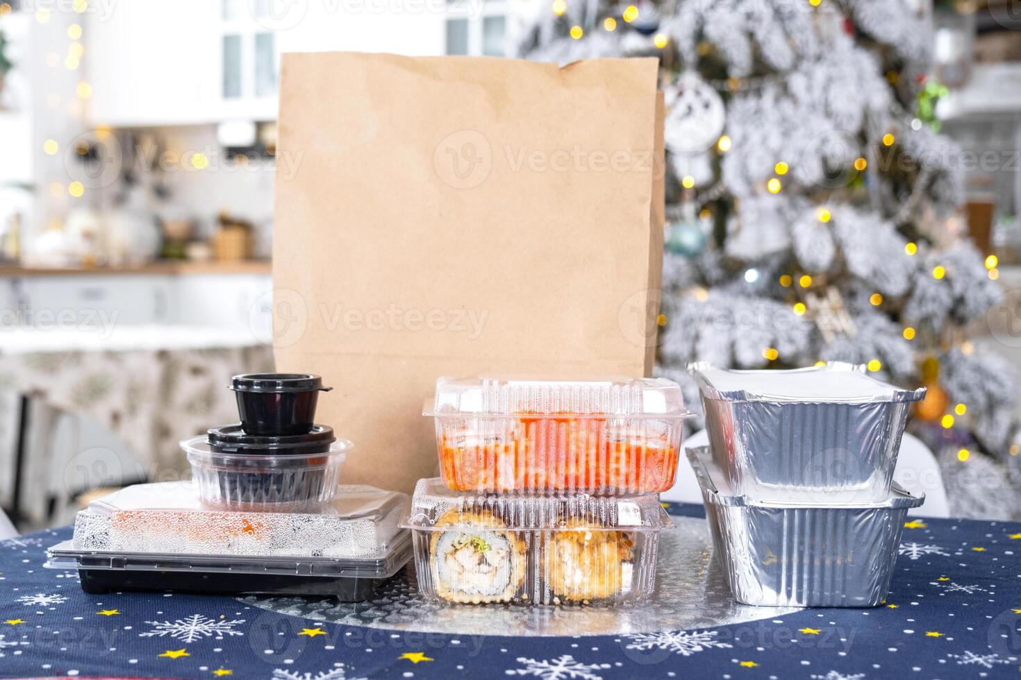 Delivery of sushi and rolls in food containers on the table in the festive interior of the kitchen of the house with a white Christmas tree for Christmas and New year. Food delivery for the holidays photo