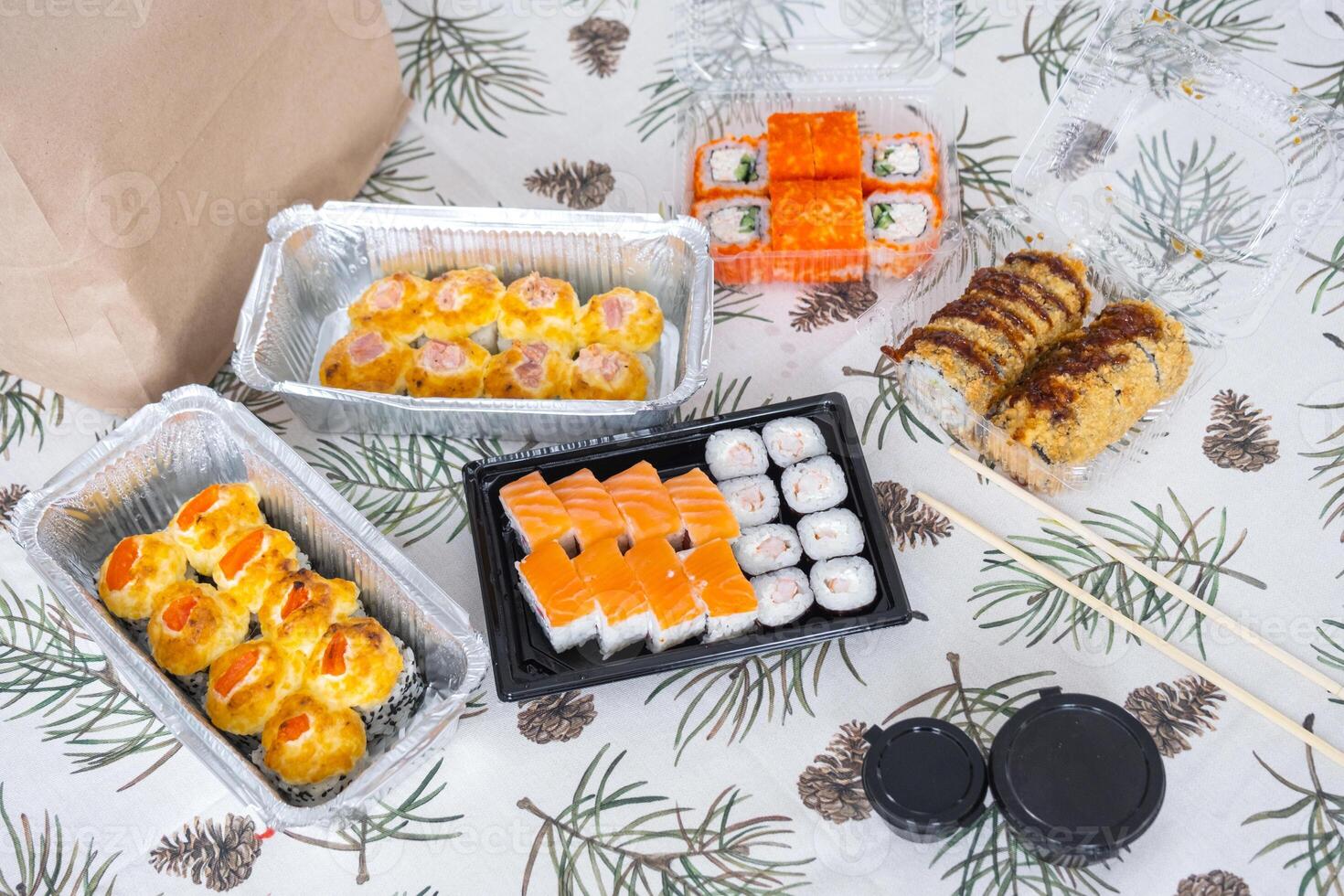 Delivery of sushi and rolls set top view on the table with a Christmas decor with a Christmas tree and a tablecloth with snowflakes, home cooking photo