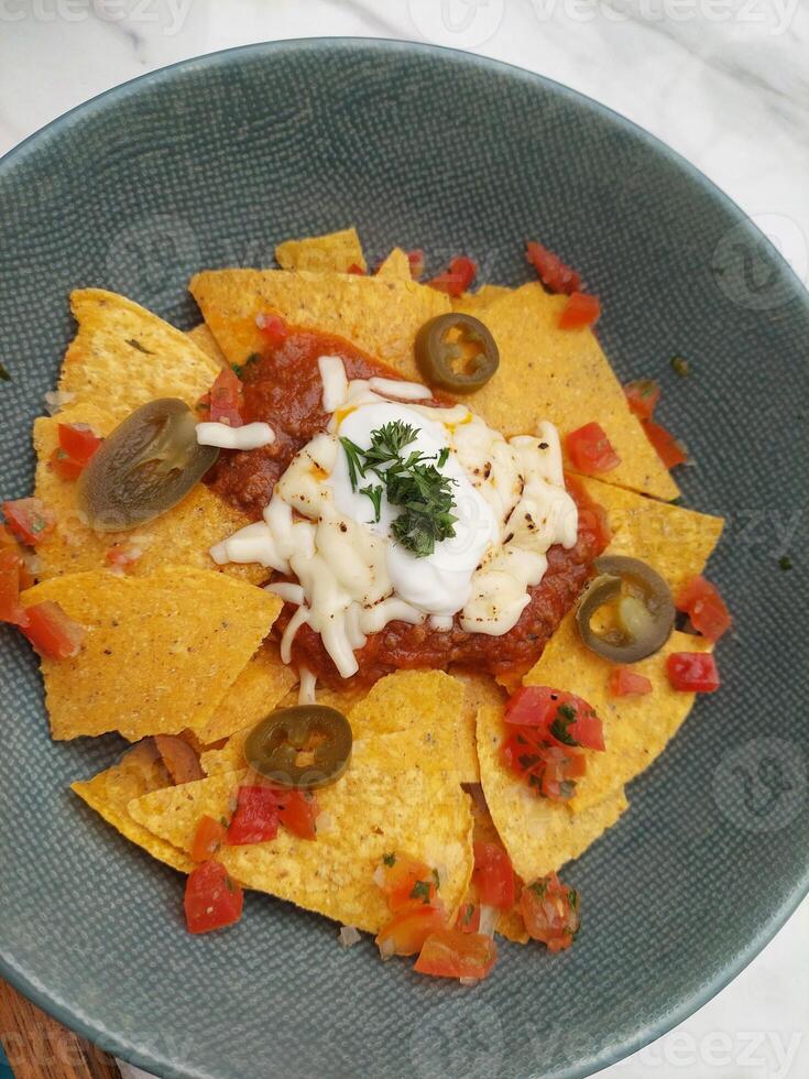 Nachos with sour cream and salsa in a blue bowl photo