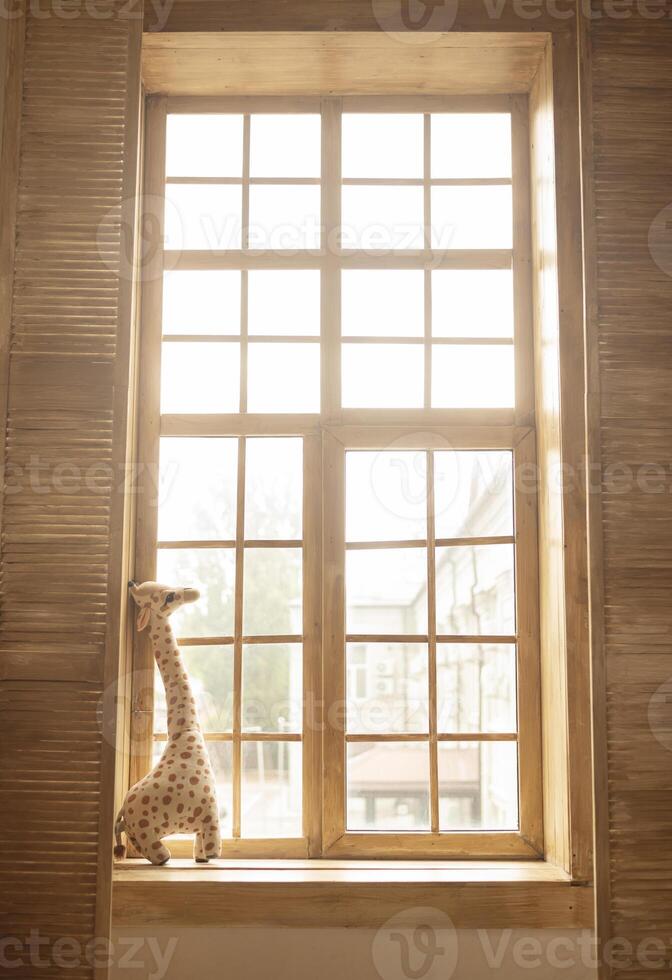 soft plush toy giraffe on a wooden windowsill. sunny days. children room photo