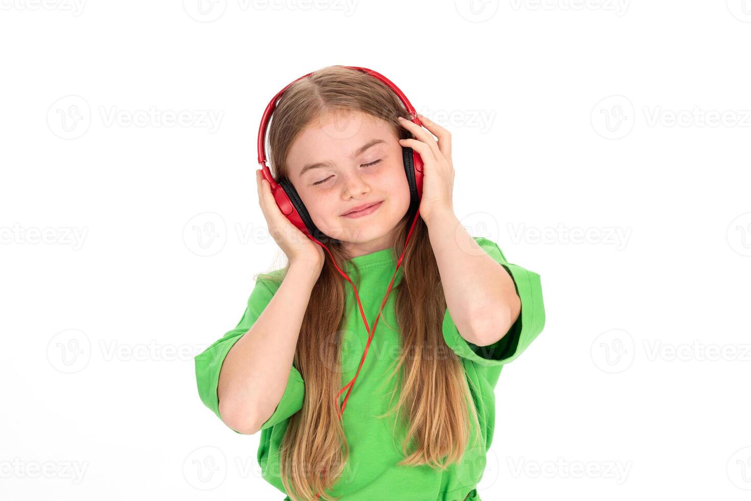 Happy girl in green summer outfit dancing enjoying music in red headphones on white background photo