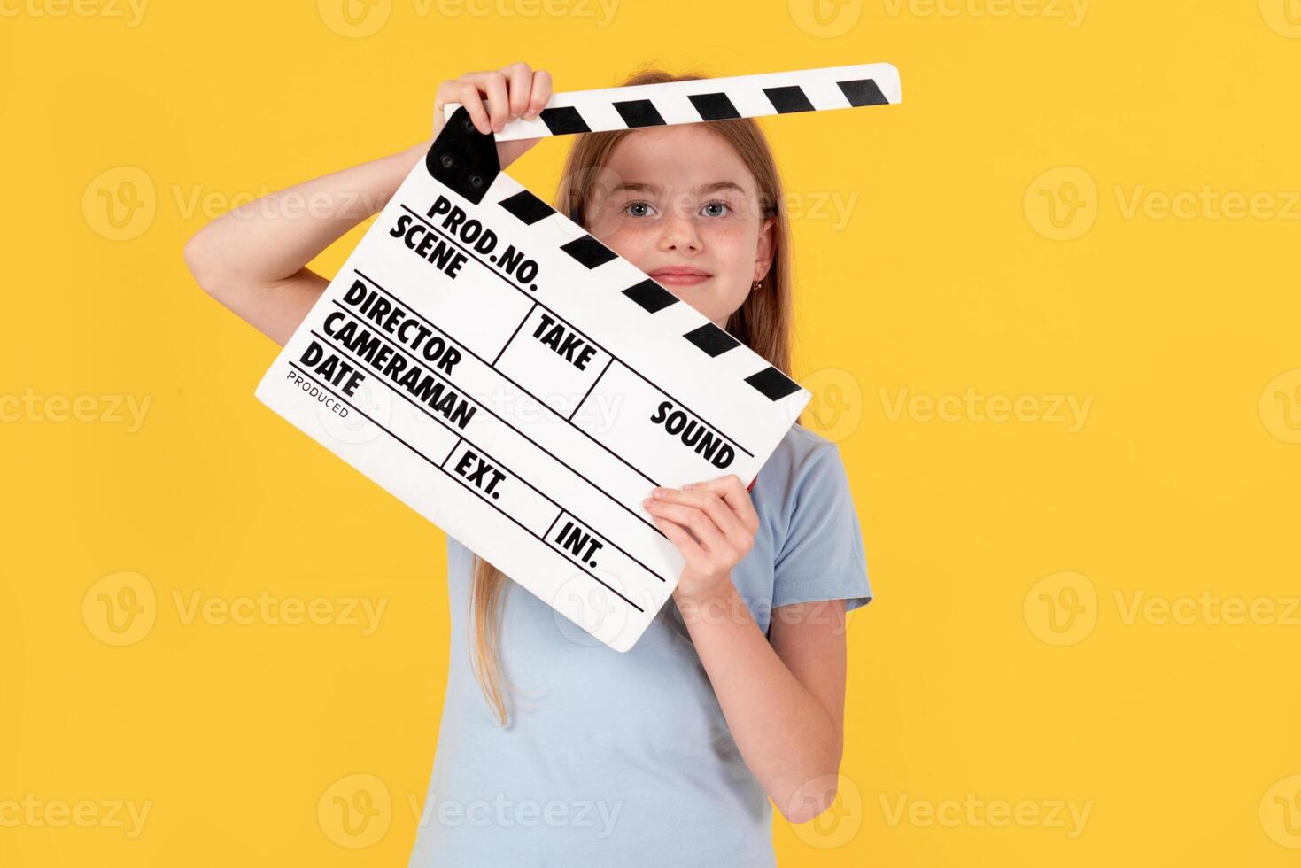 Little child girl wear blue t-shirt holding clapperboard isolated on yellow background. Children lifestyle childhood concept. photo