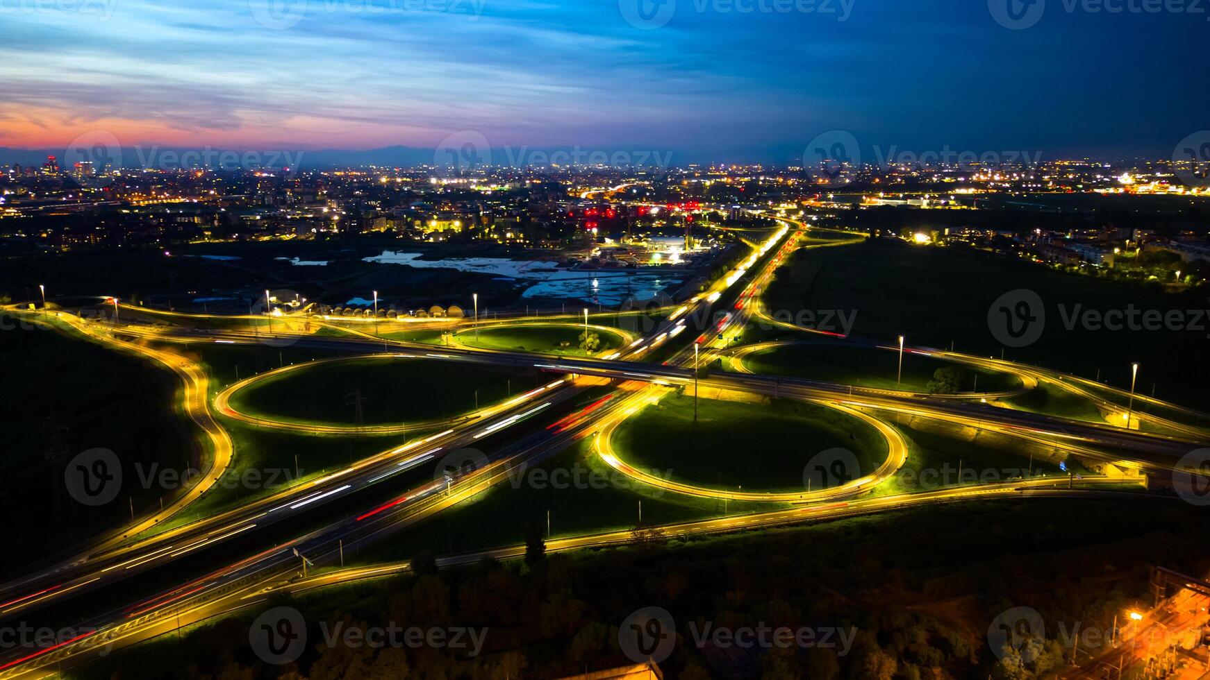 Aerial view huge multi-lane circle roundabout intersection in city traffic highway night city. Public transport commuter pollution business concept. Milan, Italy. photo
