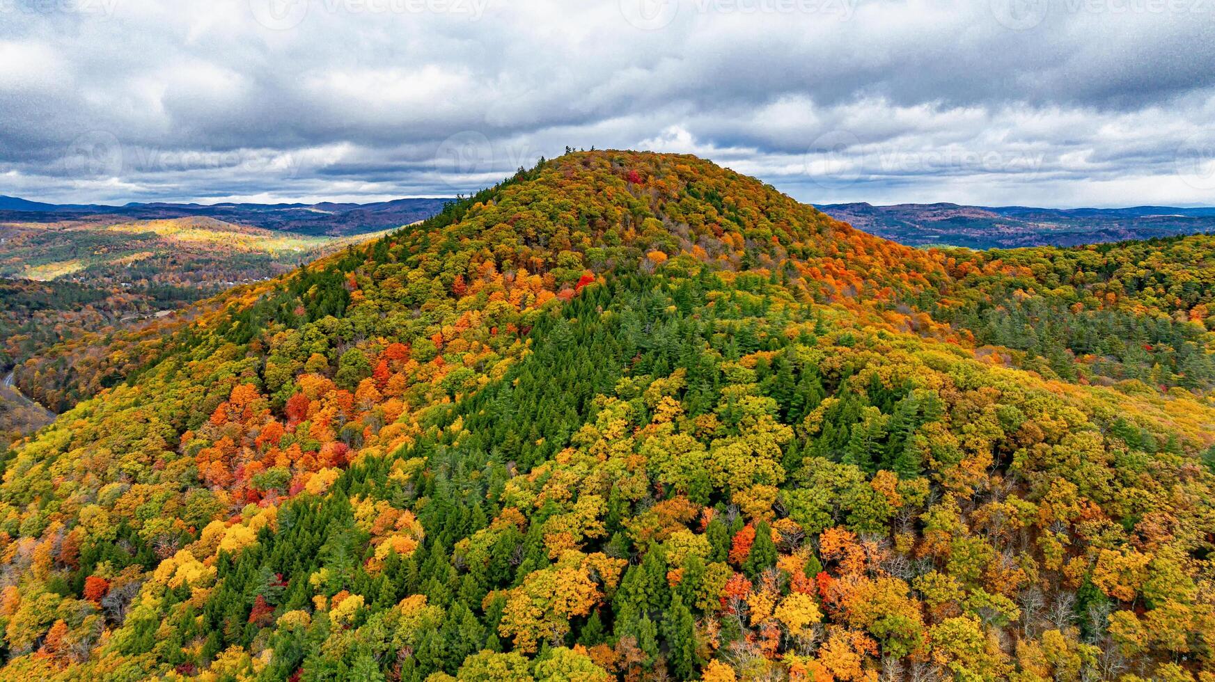 Autumn hues blanket the USA's hills. Vivid autumn foliage covers rolling hills as clouds hover above, showcasing nature's stunning transformation during fall. photo