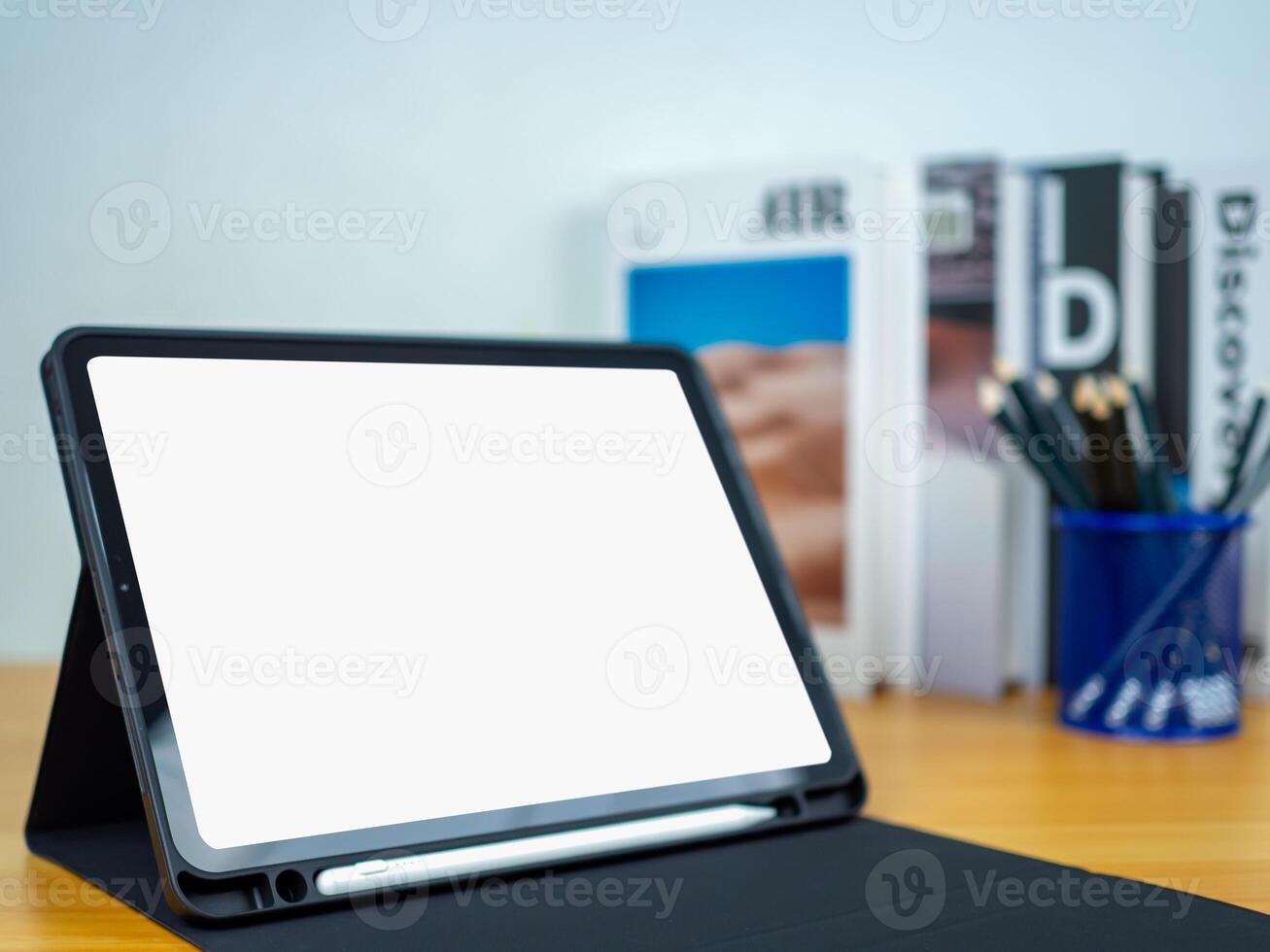 Tablet with blank screen on wooden table. Office supplies, Books on wooden table and white wall. Space for copying your text, Workspace and copy space, Desk with office supplies. photo