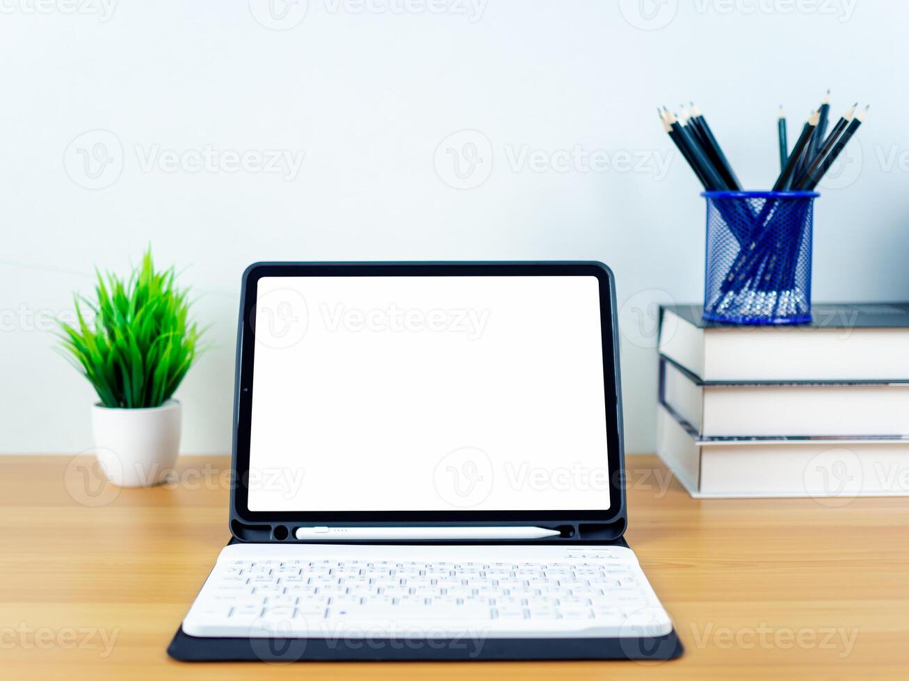 Tablet with blank screen on wooden table. Office supplies, Books, Indoor plants, on wooden table and white wall. Space for copying your text, Workspace and copy space, Desk with office supplies. photo