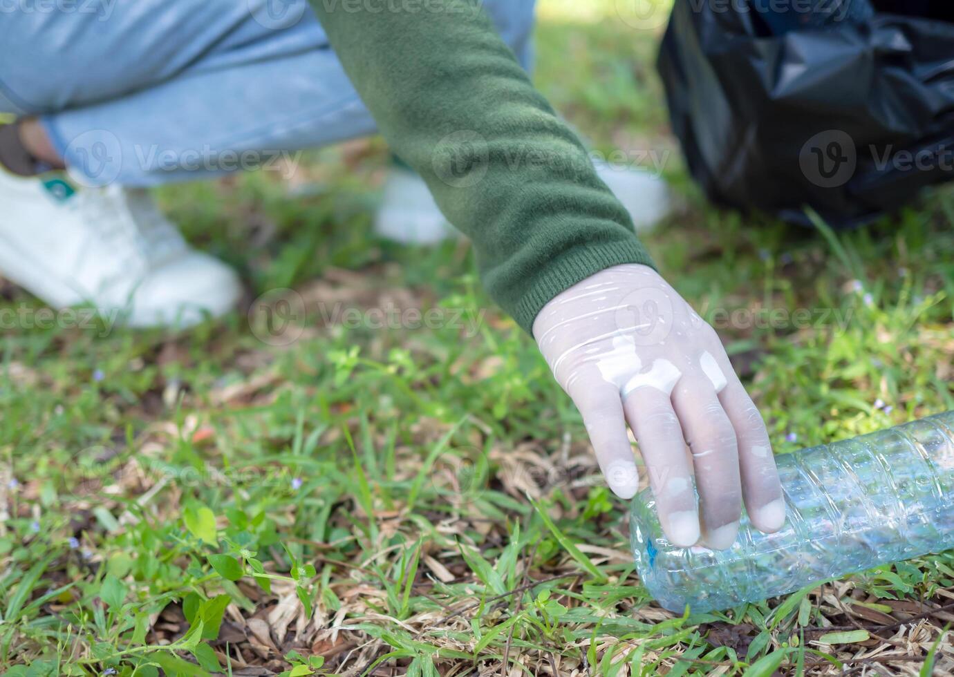 Woman of dedicated volunteers are participating in an environmental cleaning activity in a park. Woman wearing gloves and hold large black bags. Woman collecting trash and plastic bottles in a park. photo