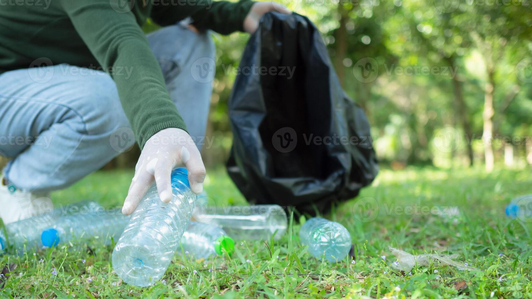 Woman of dedicated volunteers are participating in an environmental cleaning activity in a park. Woman wearing gloves and hold large black bags. Woman collecting trash and plastic bottles in a park. photo