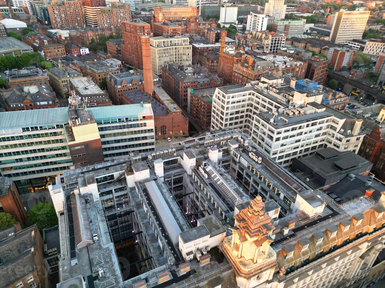 Aerial View of Greater Manchester City Centre and Tall Buildings During Golden Hour of Sunset. England UK. High Angle Footage Was Captured with Drone's Camera During Windy day of May 5th, 2024 photo