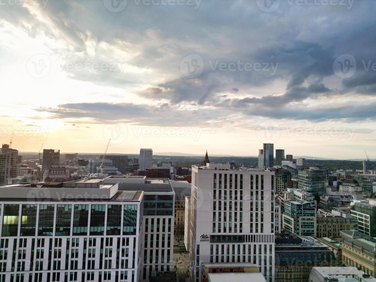 Aerial View of Greater Manchester City Centre and Tall Buildings During Golden Hour of Sunset. England UK. High Angle Footage Was Captured with Drone's Camera During Windy day of May 5th, 2024 photo