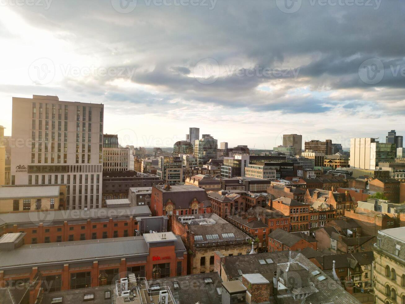 Aerial View of Greater Manchester City Centre and Tall Buildings During Golden Hour of Sunset. England UK. High Angle Footage Was Captured with Drone's Camera During Windy day of May 5th, 2024 photo