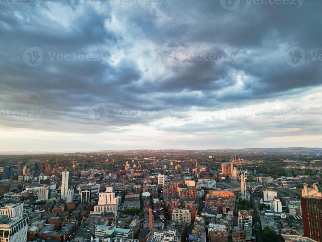 Aerial View of Greater Manchester City Centre and Tall Buildings During Golden Hour of Sunset. England UK. High Angle Footage Was Captured with Drone's Camera During Windy day of May 5th, 2024 photo
